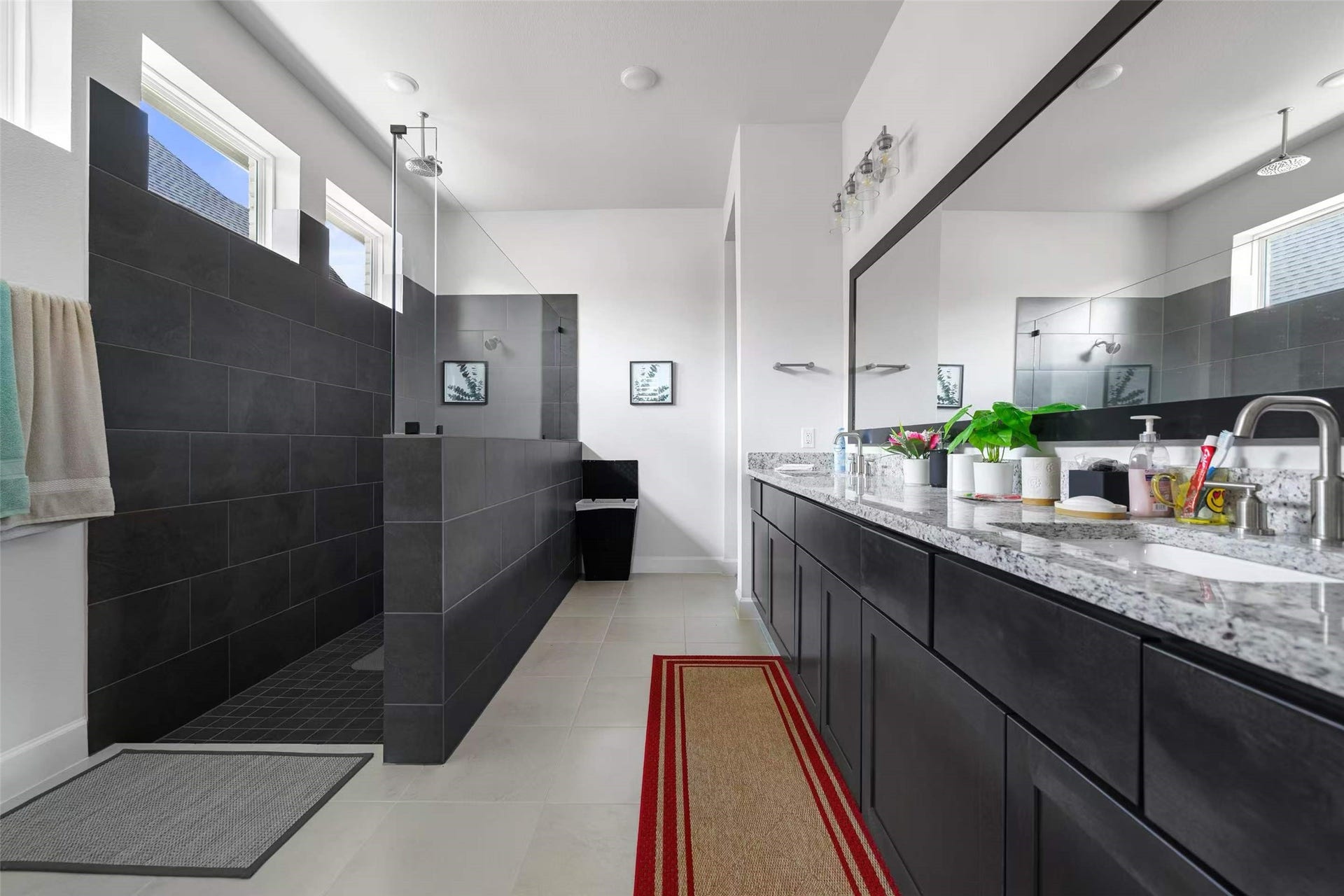 Luxurious primary bathroom featuring an upgraded oversized walk-in shower with sleek floor-to-ceiling tile, frameless glass enclosure, and an elegant dual-sink vanity with granite countertops.