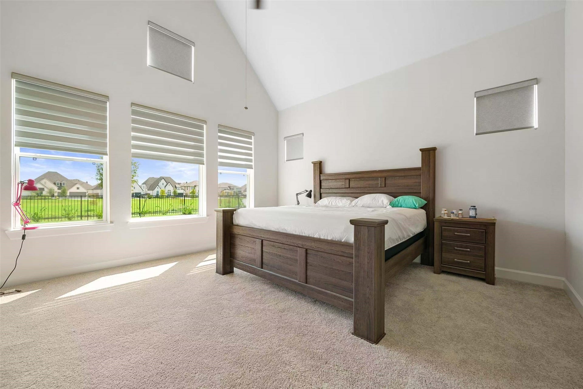 Spacious primary suite featuring soaring vaulted ceilings, abundant natural light, and beautiful lake views through oversized windows.