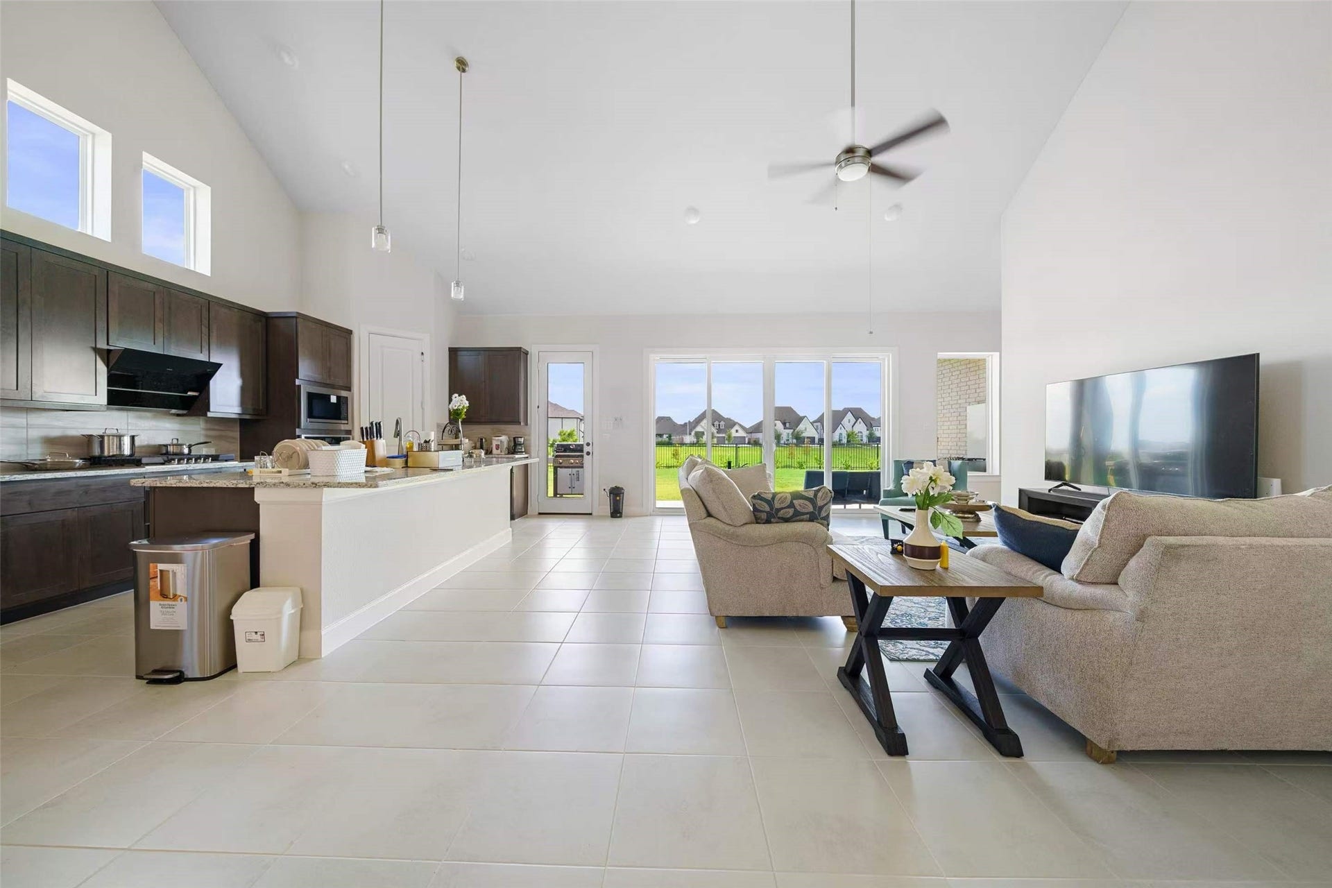 Stunning open-concept living area with soaring ceilings, abundant natural light, and expansive sliding glass doors showcasing beautiful lake views. Enjoy seamless indoor-outdoor living in this thoughtfully designed one-story home.