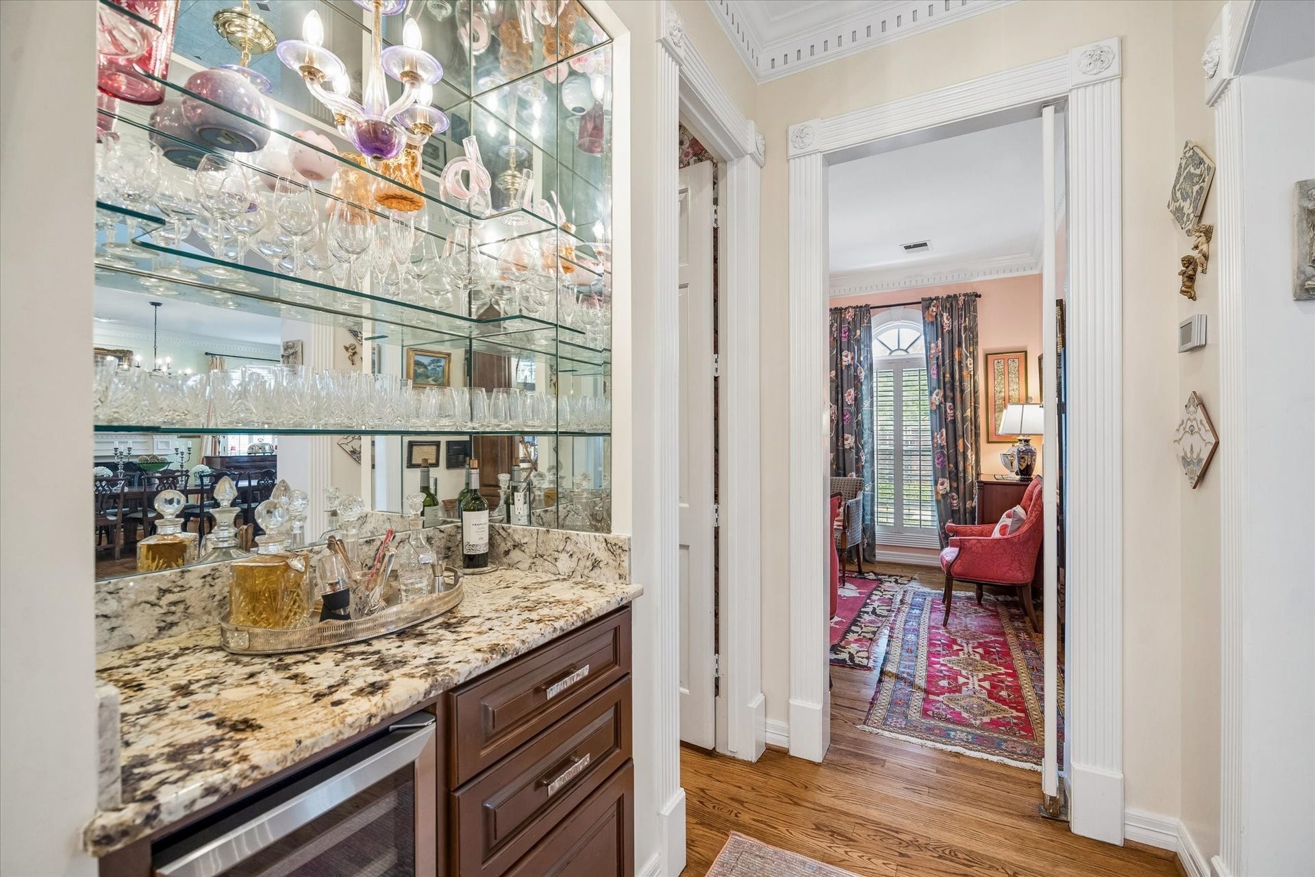 2120 Potomac Drive, #A, Houston, TX 77057 The dry bar is conveniently situated between the formal living room and the kitchen. Glass shelves, a mirror backing, and granite countertop complement the space. The bar also features a wine refrigerator and storage.