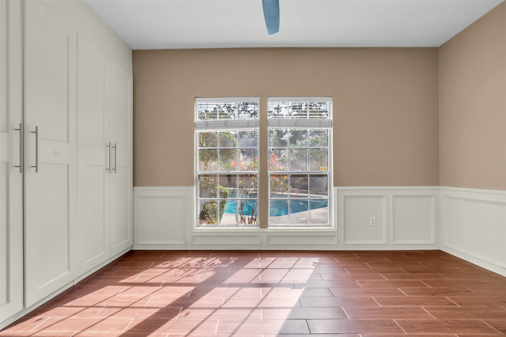 14014 Court Of Regents, Houston, TX 77069 Secondary bedroom on the first floor featuring large windows with views of the backyard pool, allowing ample natural light to fill the space throughout the day.