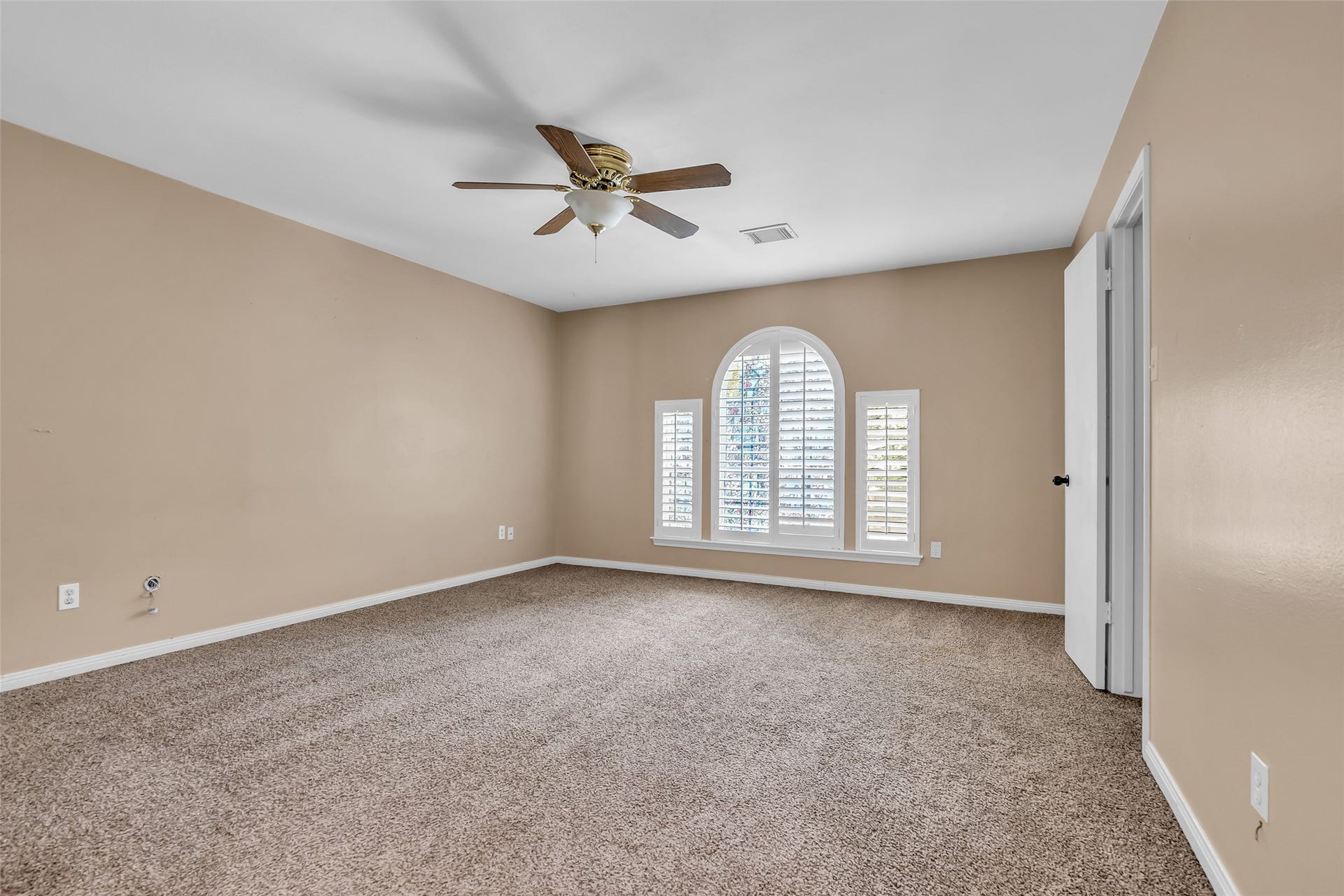 14014 Court Of Regents, Houston, TX 77069 Carpeted bedroom on the second floor with windows overlooking the front lawn, complemented by a ceiling fan to enhance airflow and comfort.