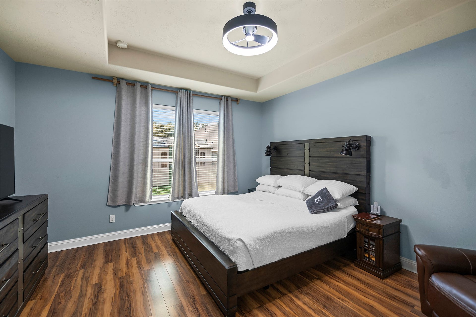 The primary bedroom is located on the first floor and features elegant flooring paired with a modern light fixture.