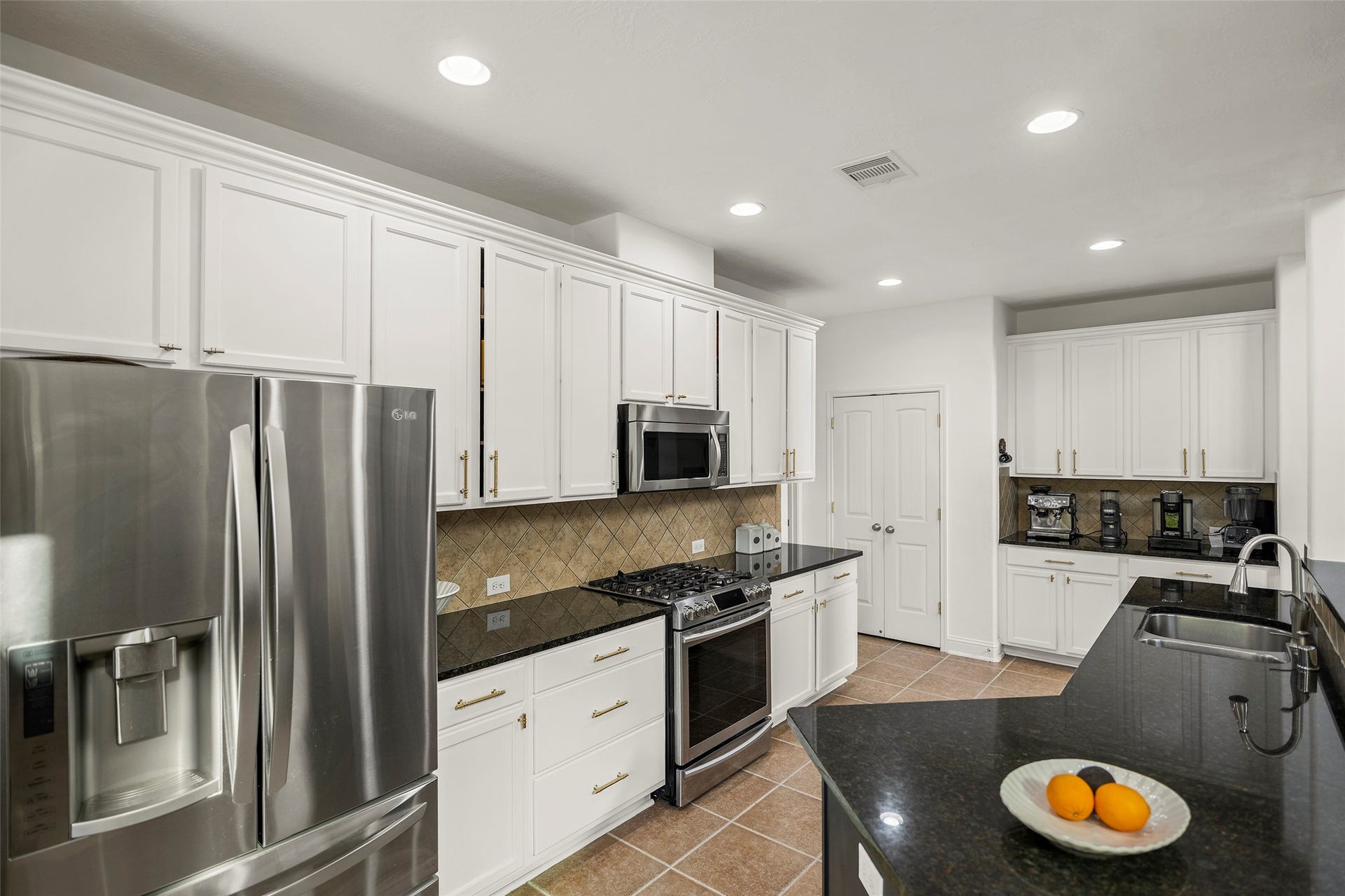This spacious, modern kitchen features an abundance of cabinetry, complemented by sleek granite countertops and a stylish tile backsplash.