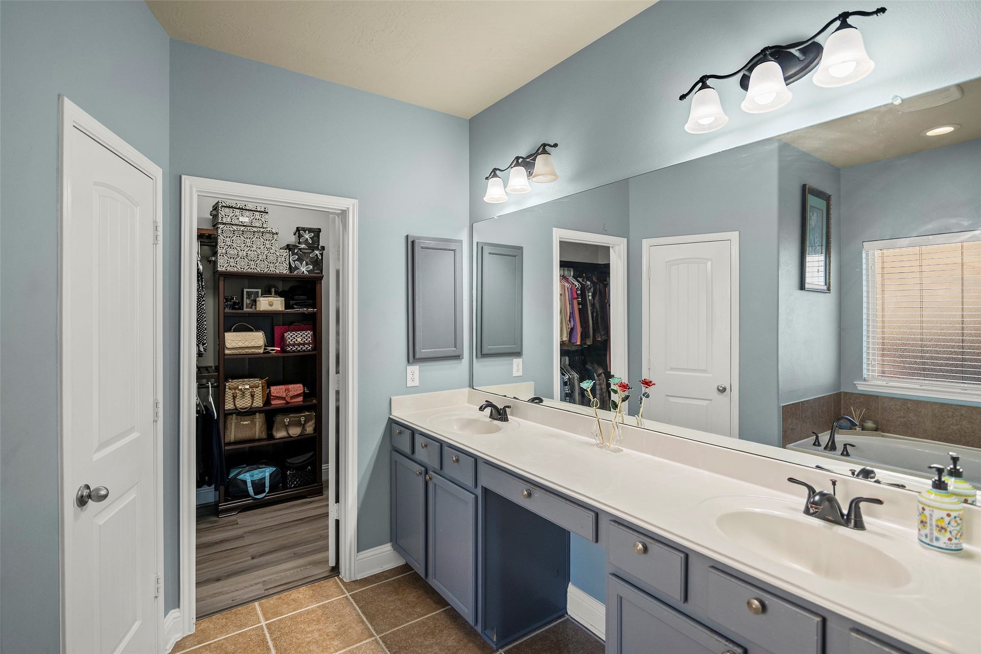 The primary bathroom features a double vanity, a spacious garden tub, a separate glass-enclosed shower, and a large walk-in closet.
