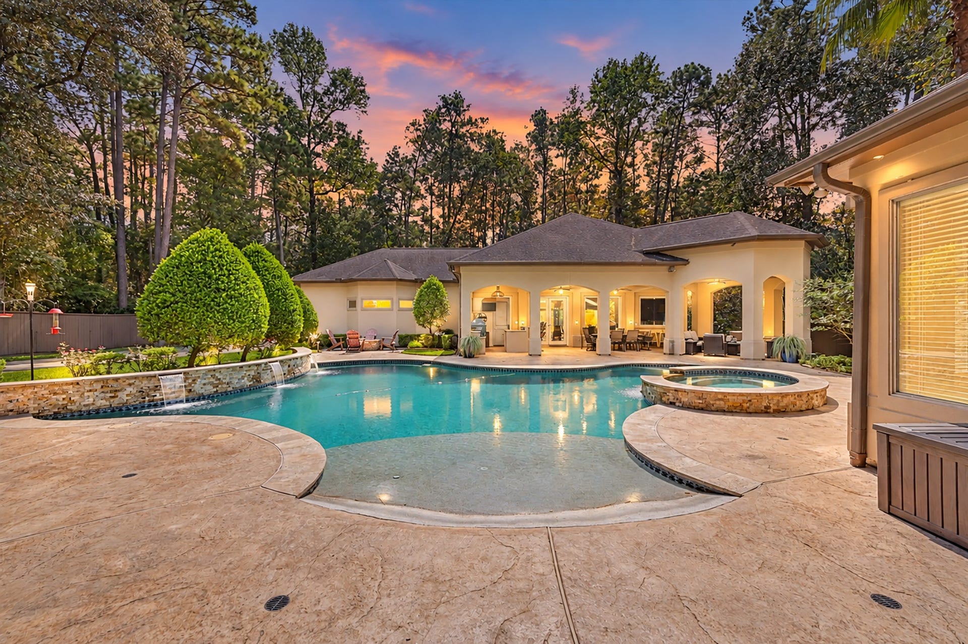 27706 Braydon Court, Spring, TX 77386 Luxurious backyard oasis featuring a sparkling pool and spa, surrounded by lush greenery and elegant patio spaces, perfect for relaxing and entertaining.
