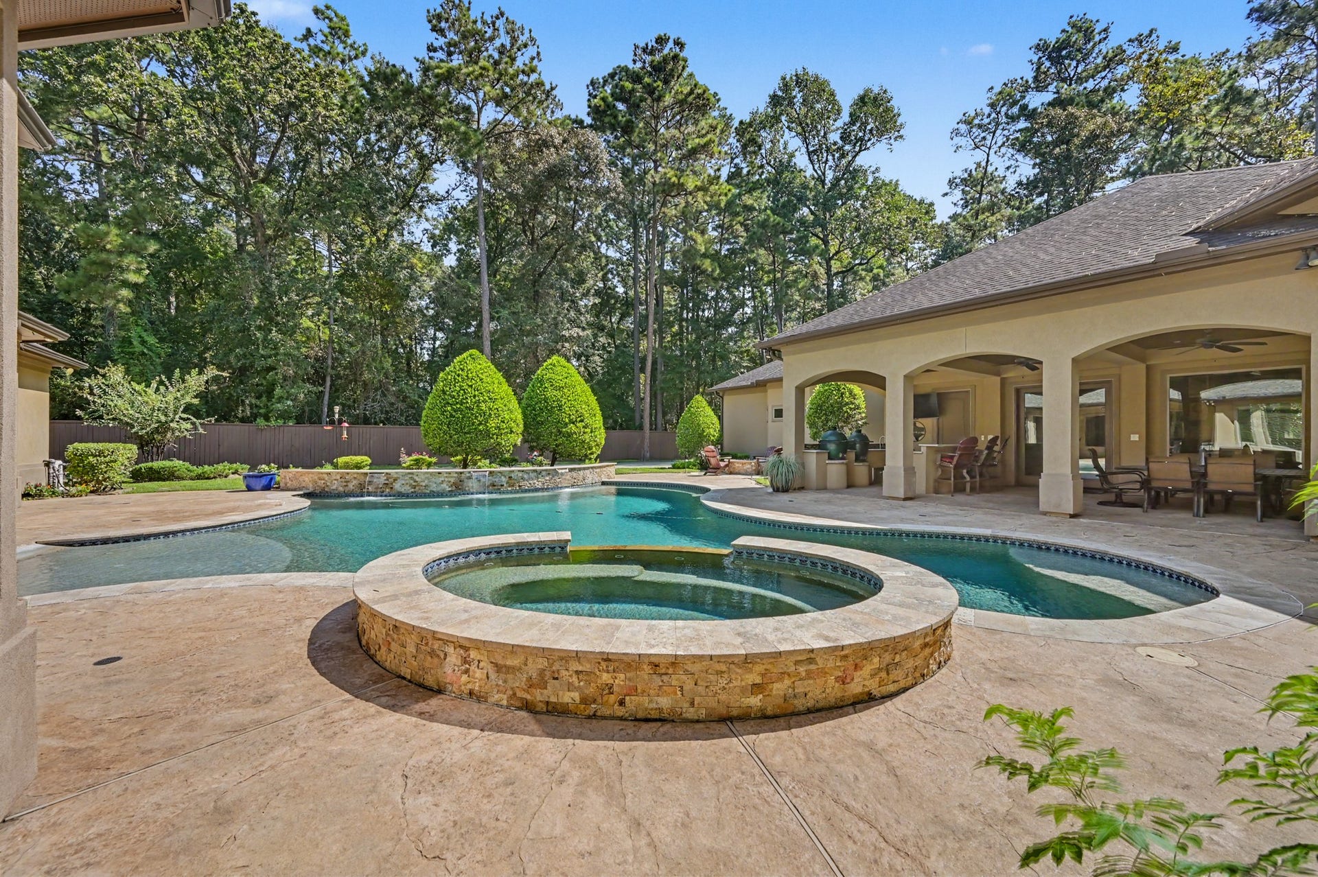 27706 Braydon Court, Spring, TX 77386 Luxurious backyard oasis featuring a sparkling pool with a spa, surrounded by lush landscaping and a spacious covered patio perfect for entertaining.