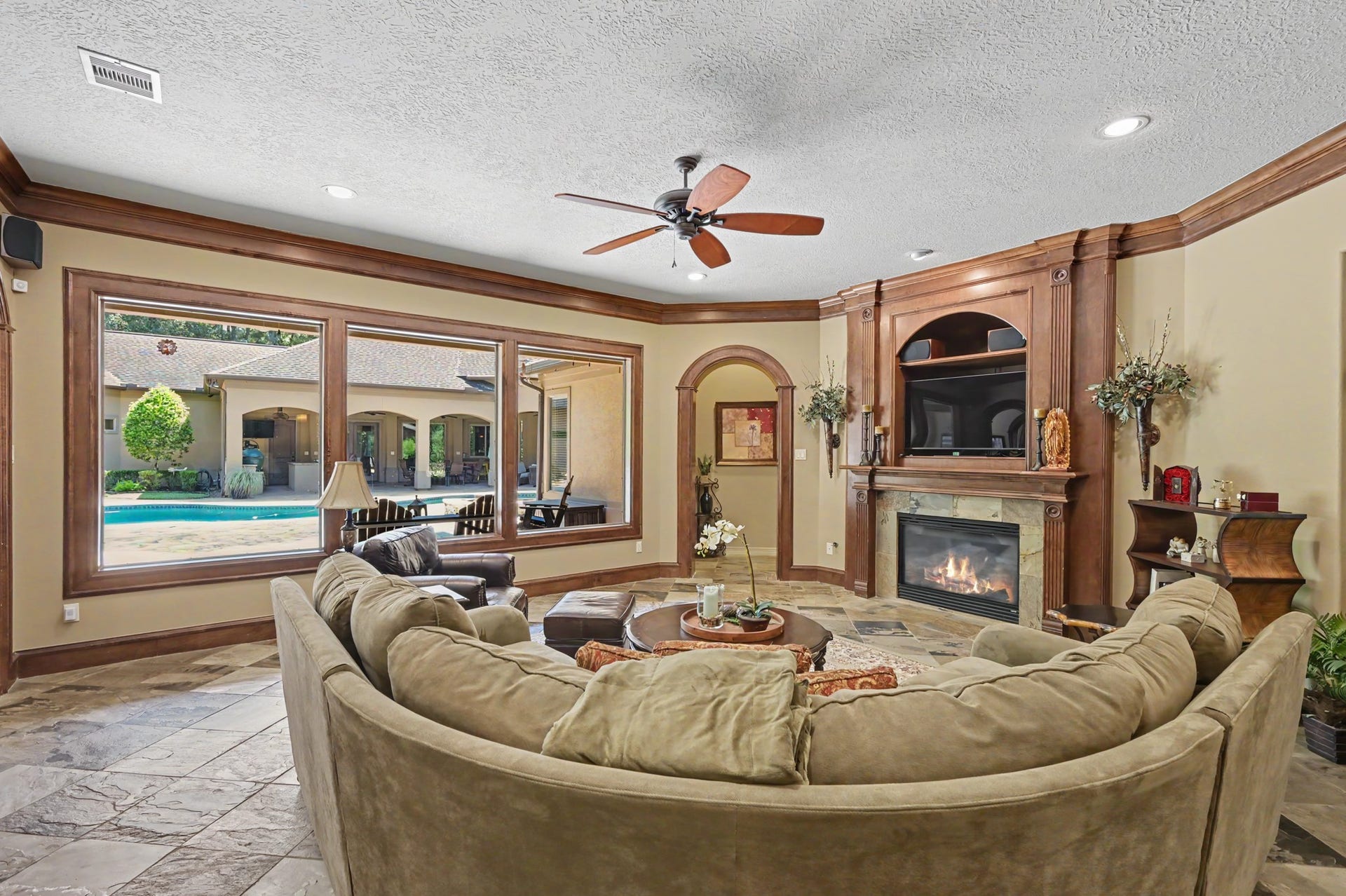 27706 Braydon Court, Spring, TX 77386 Living room featuring a cozy fireplace and expansive windows offering a stunning view of the pool and outdoor area.