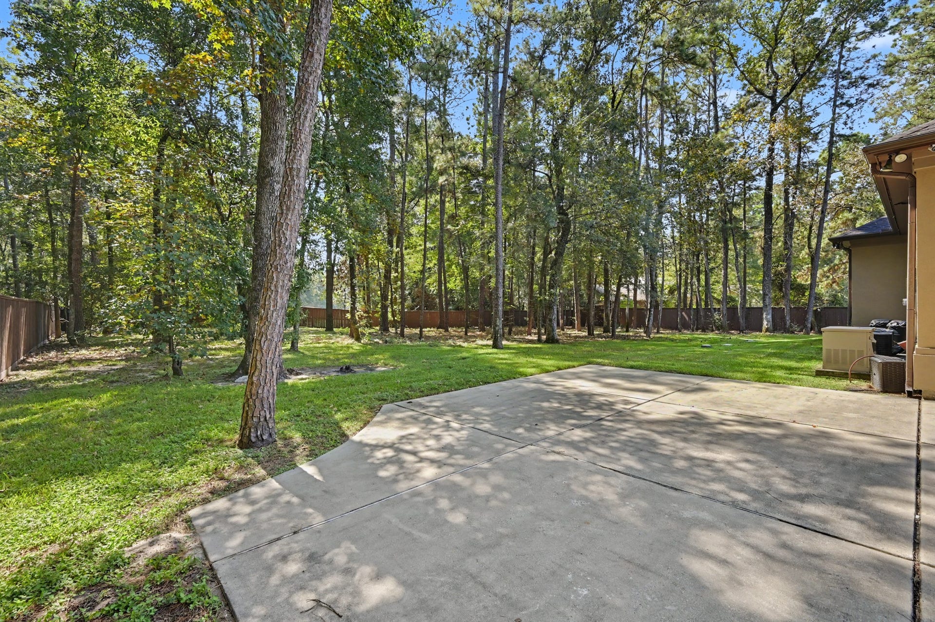 27706 Braydon Court, Spring, TX 77386 Expansive backyard with a large, paved patio area surrounded by lush trees, offering a perfect blend of nature and outdoor living space.