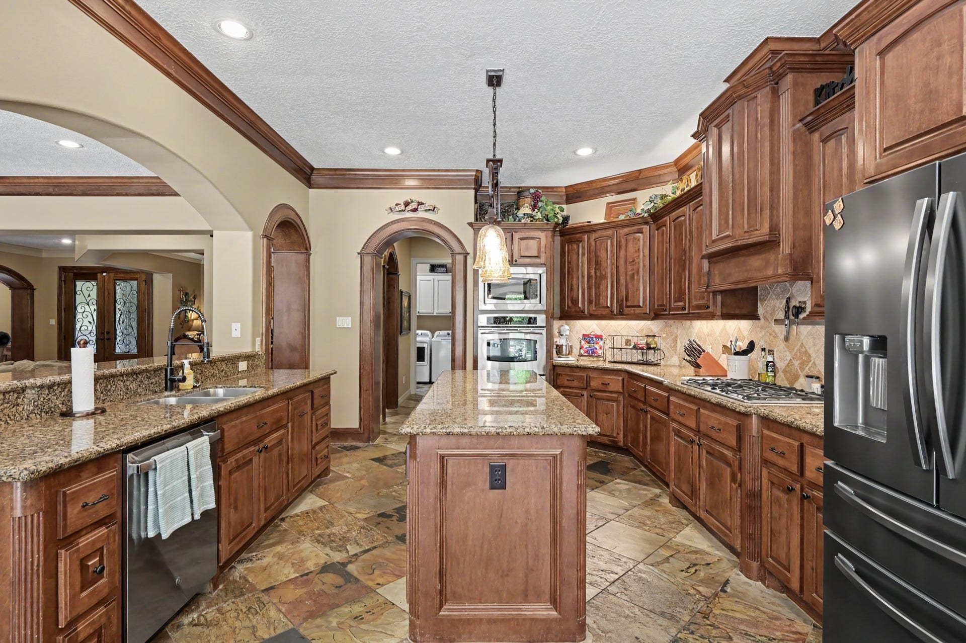 27706 Braydon Court, Spring, TX 77386 Another view of the kitchen with rich wooden cabinetry, granite countertops, and modern appliances, offering a blend of oppulance and functionality.