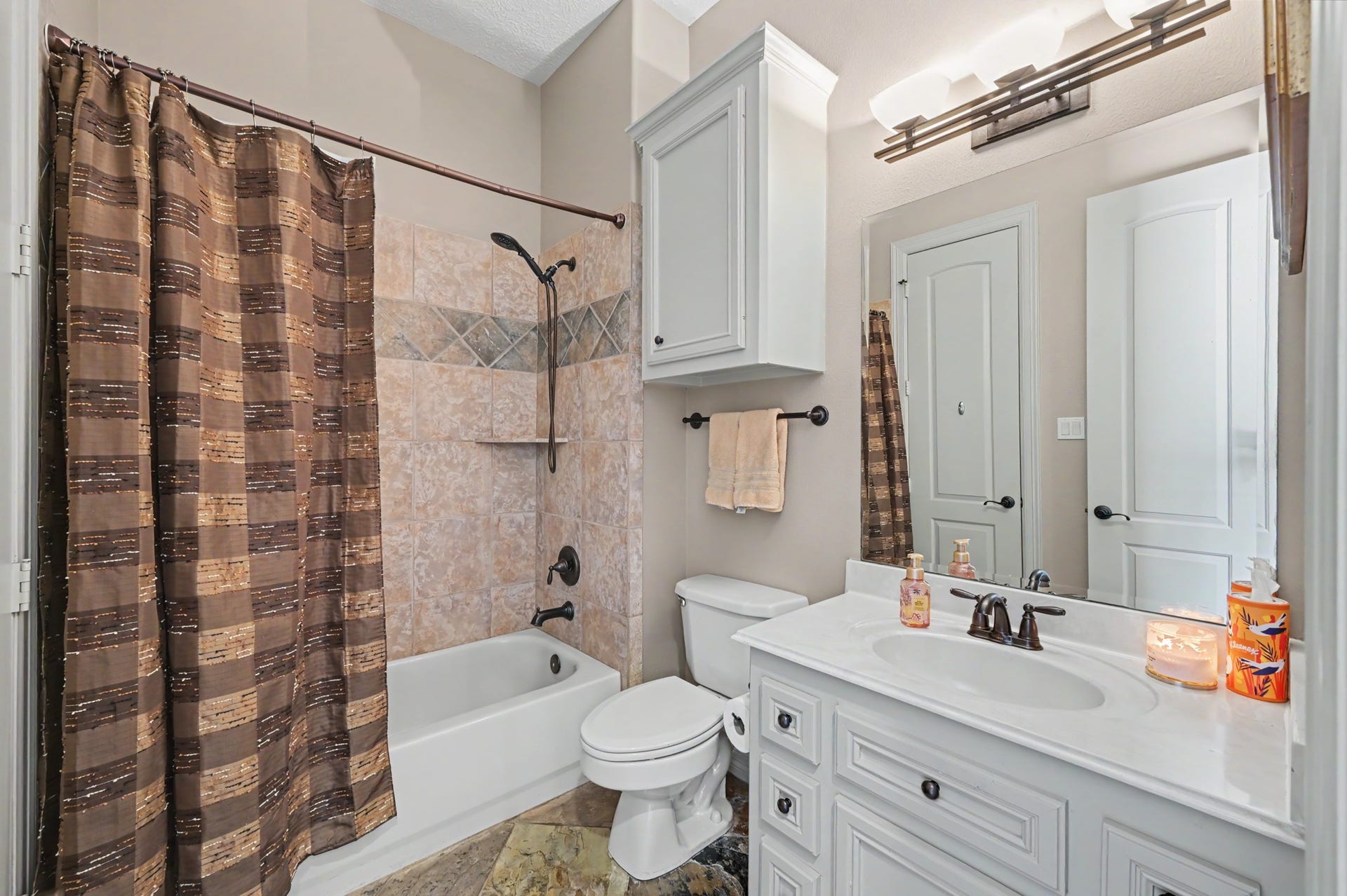 27706 Braydon Court, Spring, TX 77386 Charming second floor bathroom with a stylish tile shower, elegant vanity, and ample cabinet storage, complemented by warm lighting and tasteful decor.