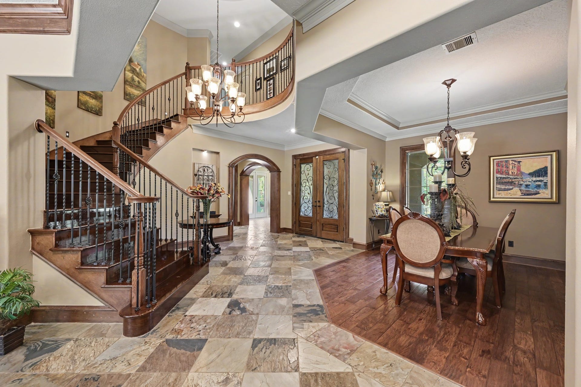 27706 Braydon Court, Spring, TX 77386 Grand entrance featuring a sweeping staircase, elegant chandelier, and a seamless blend of stone and wood flooring, leading to a sophisticated dining area.