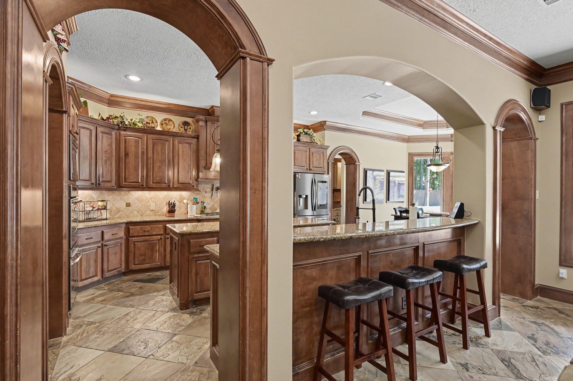 27706 Braydon Court, Spring, TX 77386 Elegant kitchen featuring rich wood cabinetry, granite countertops, and a spacious breakfast bar with seating, perfect for entertaining.