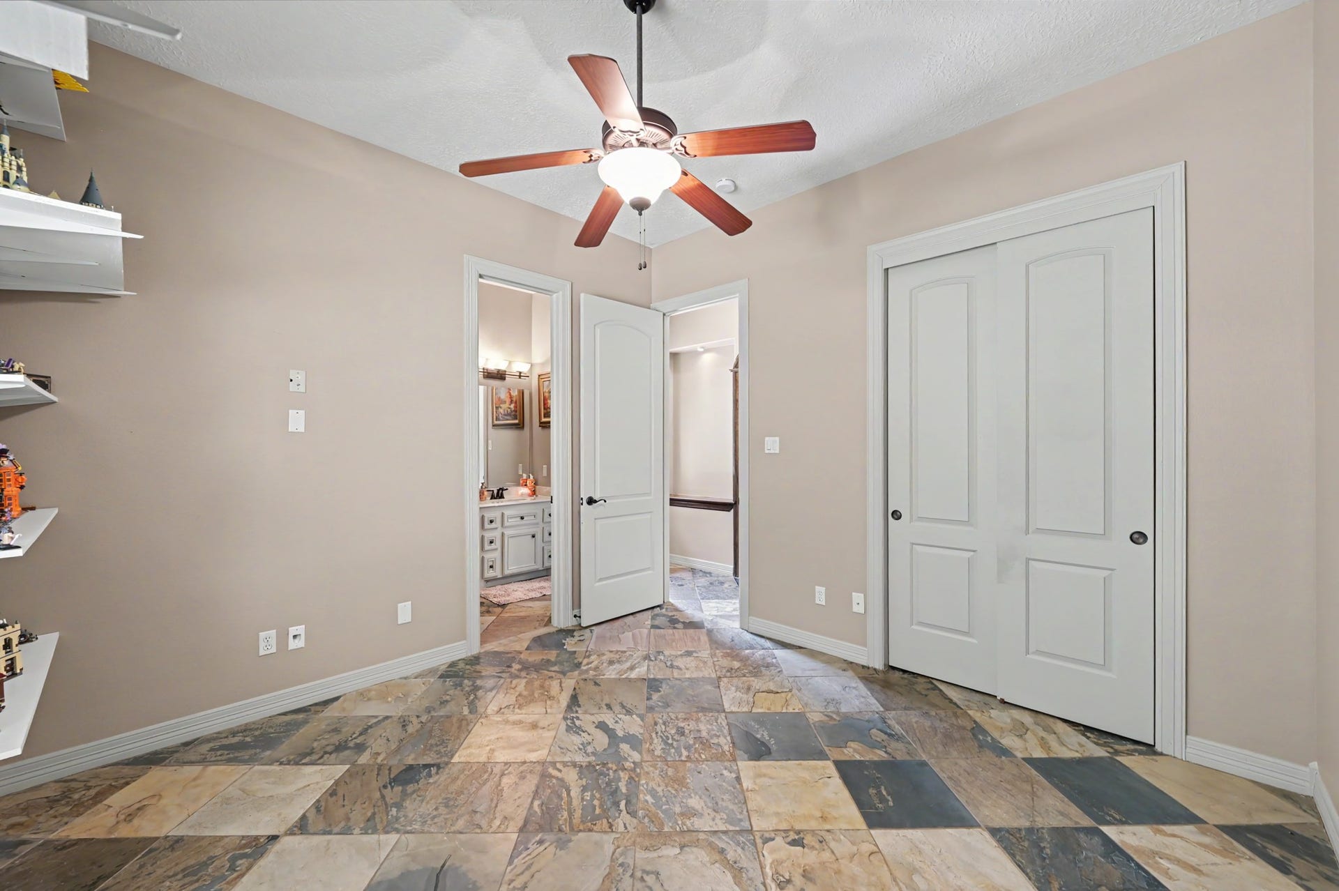 27706 Braydon Court, Spring, TX 77386 First floor secondary bedroom or craft room with elegant stone tile flooring, a ceiling fan, ample natural light, and adjoins a full bathroom.