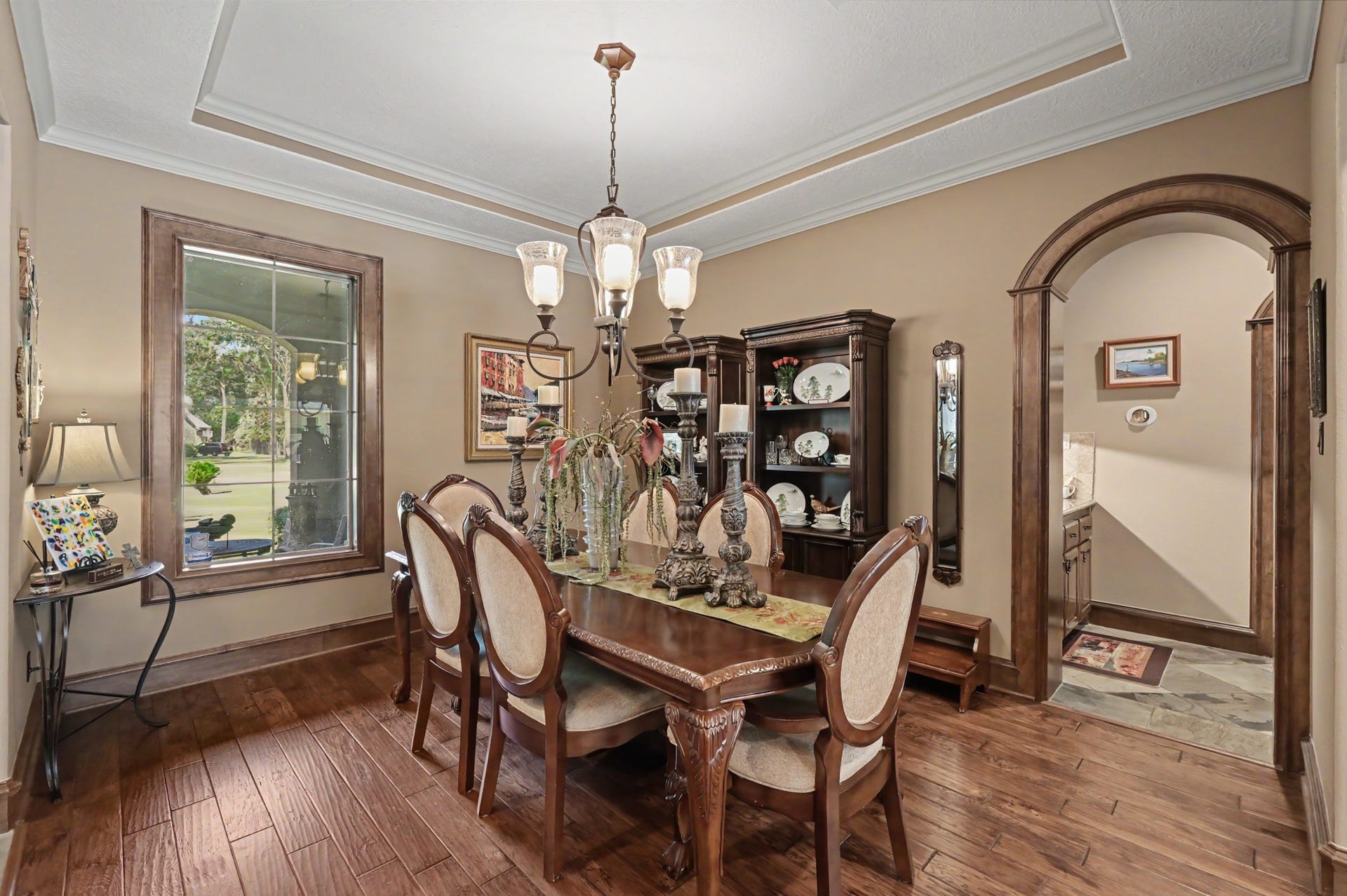 27706 Braydon Court, Spring, TX 77386 Open dining room featuring rich wood flooring, and chandelier. The space is enhanced by a large window for natural light and a stylish archway leading to an adjoining butlers pantry/wet bar.