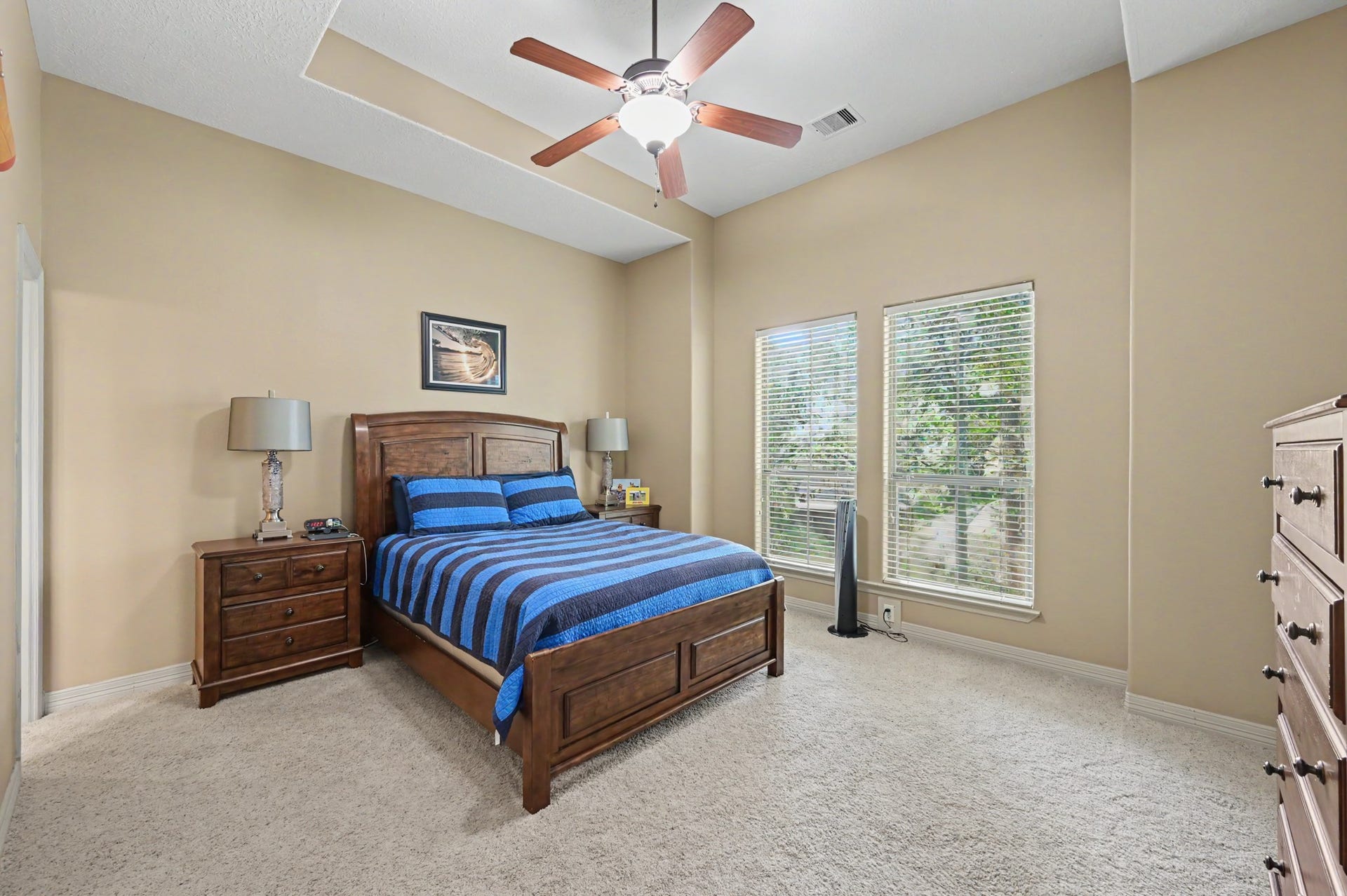 27706 Braydon Court, Spring, TX 77386 Spacious bedroom featuring a vaulted ceiling, large windows for natural light, and cozy carpet flooring, complemented by elegant wooden furniture.