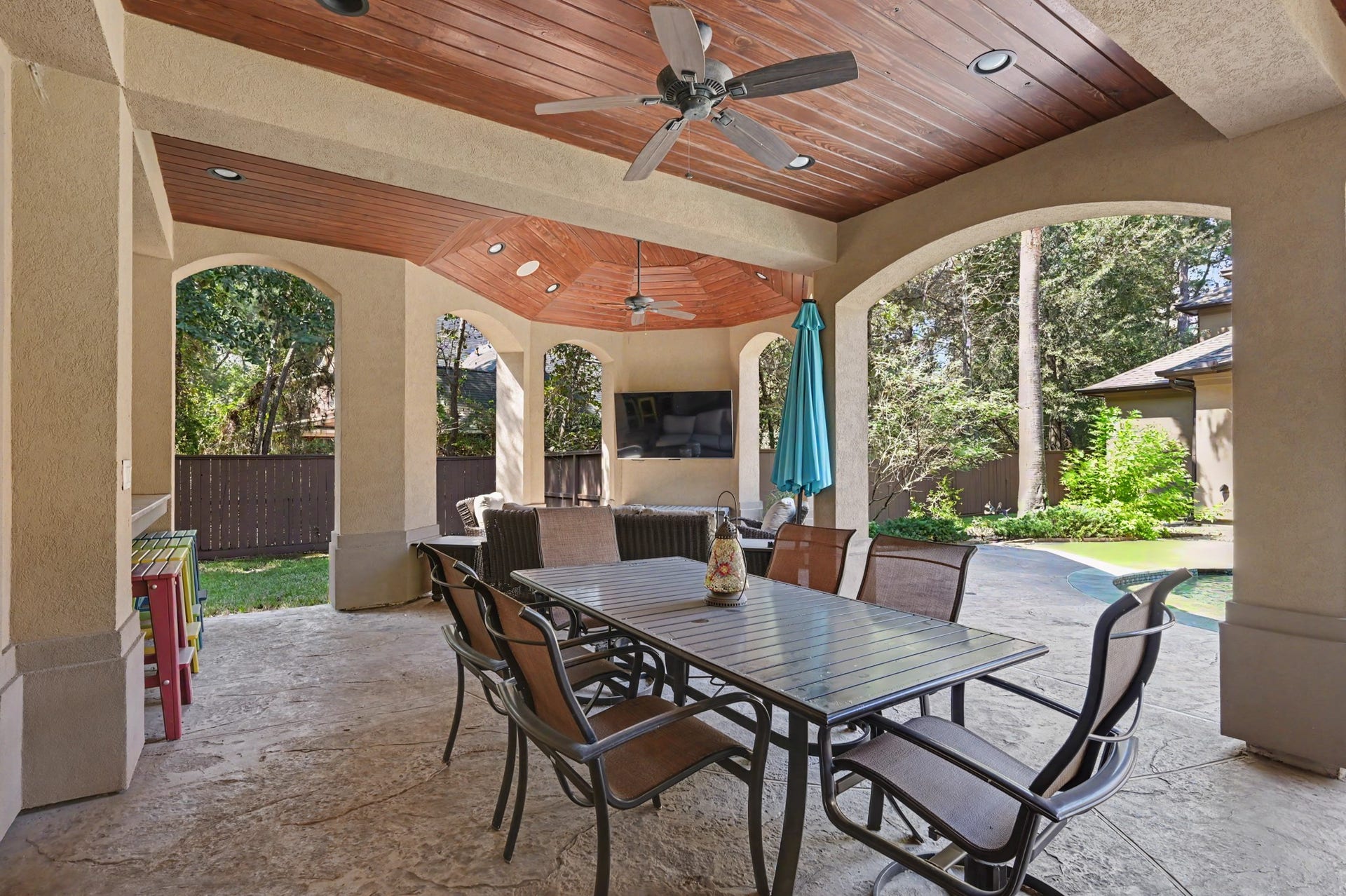 27706 Braydon Court, Spring, TX 77386 Charming outdoor patio featuring a stylish wooden ceiling, ceiling fans, and ample seating, perfect for entertaining with views of the lush backyard and pool.