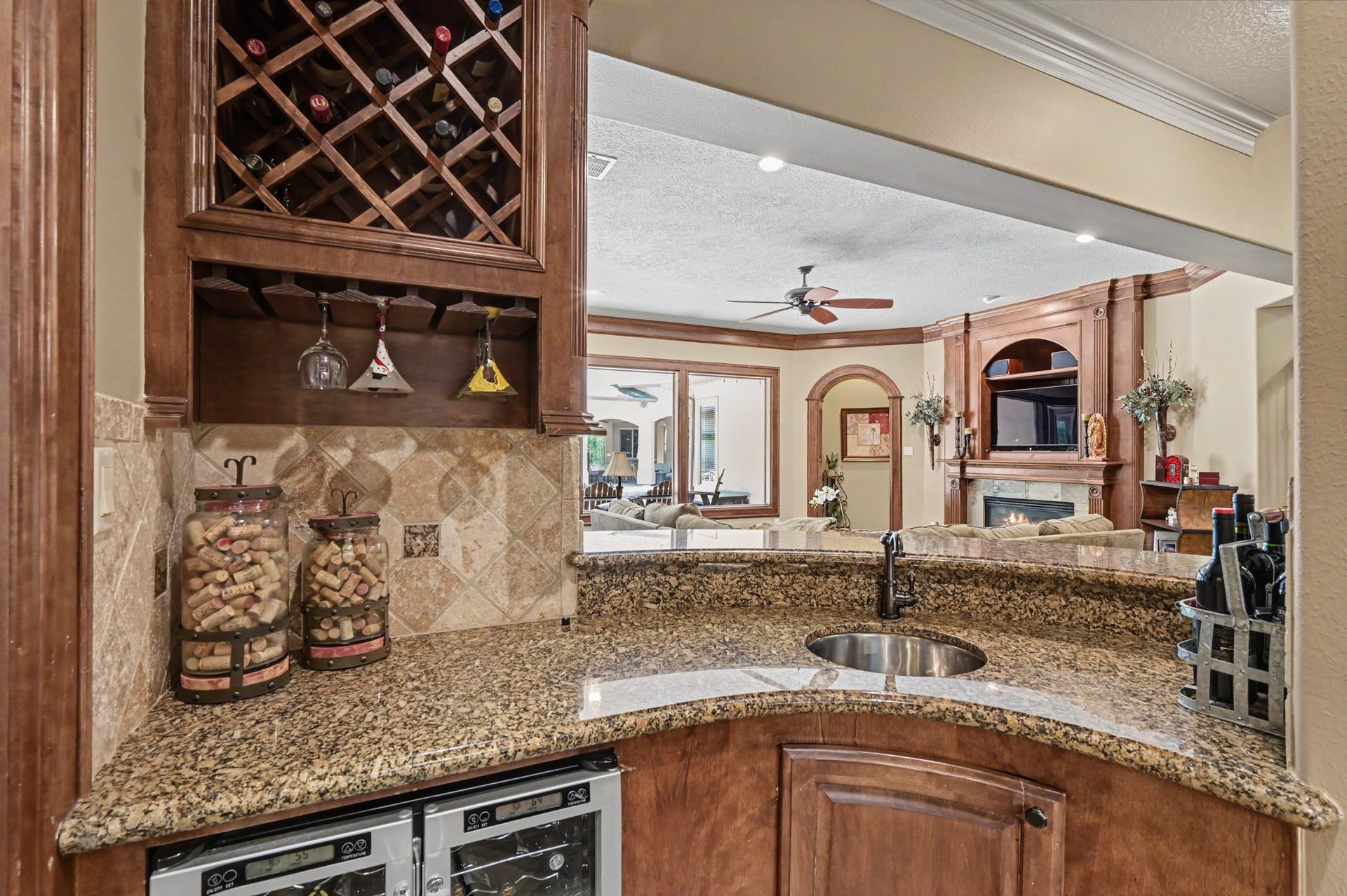 27706 Braydon Court, Spring, TX 77386 Entertain easily with a home bar with granite countertops, wine storage, and built-in glass racks, seamlessly leading into a cozy living area with a fireplace and stylish wood accents.