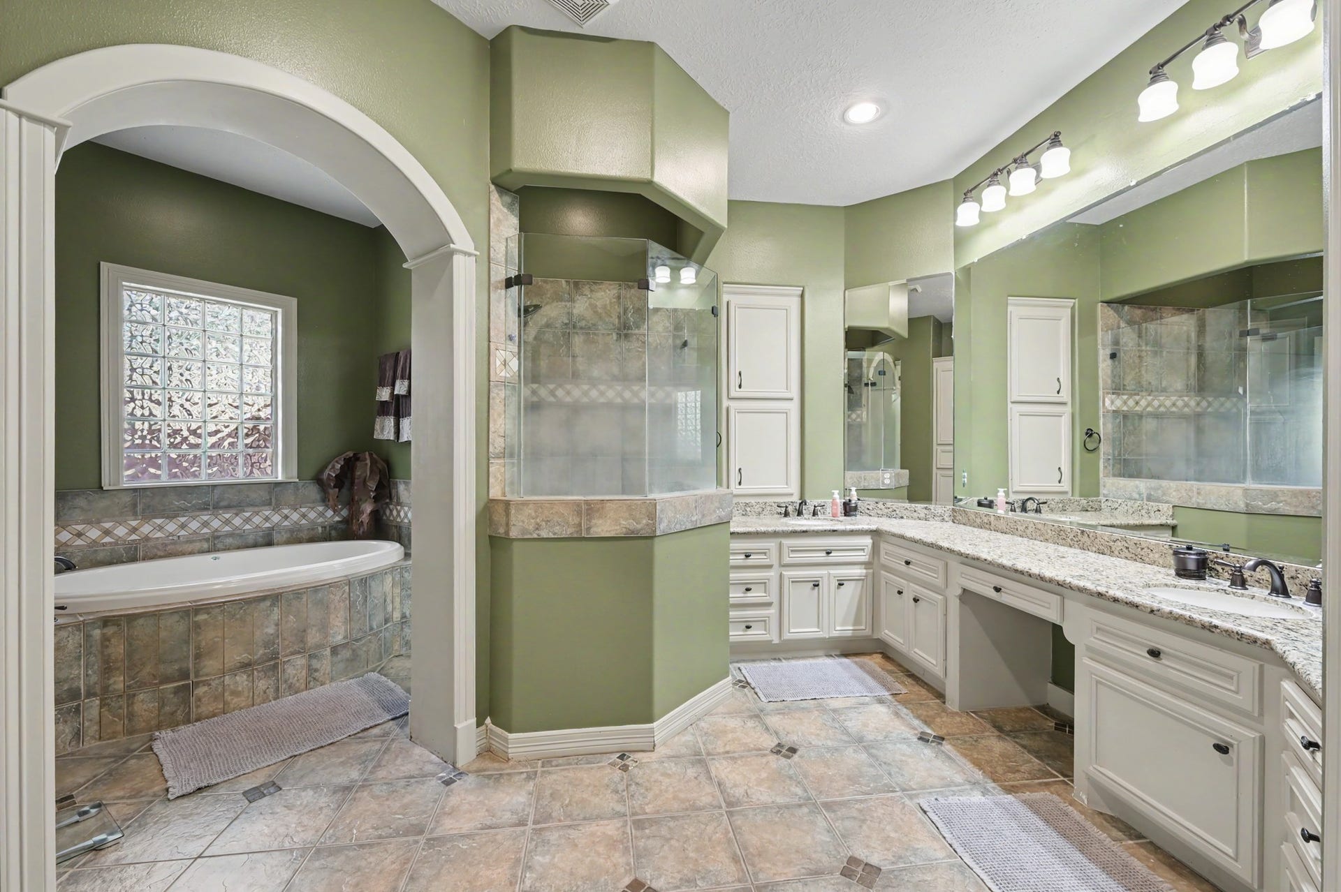 27706 Braydon Court, Spring, TX 77386 Luxurious primary bathroom featuring a soaking tub, elegant arched entry, dual vanities with granite countertops, and ample storage.