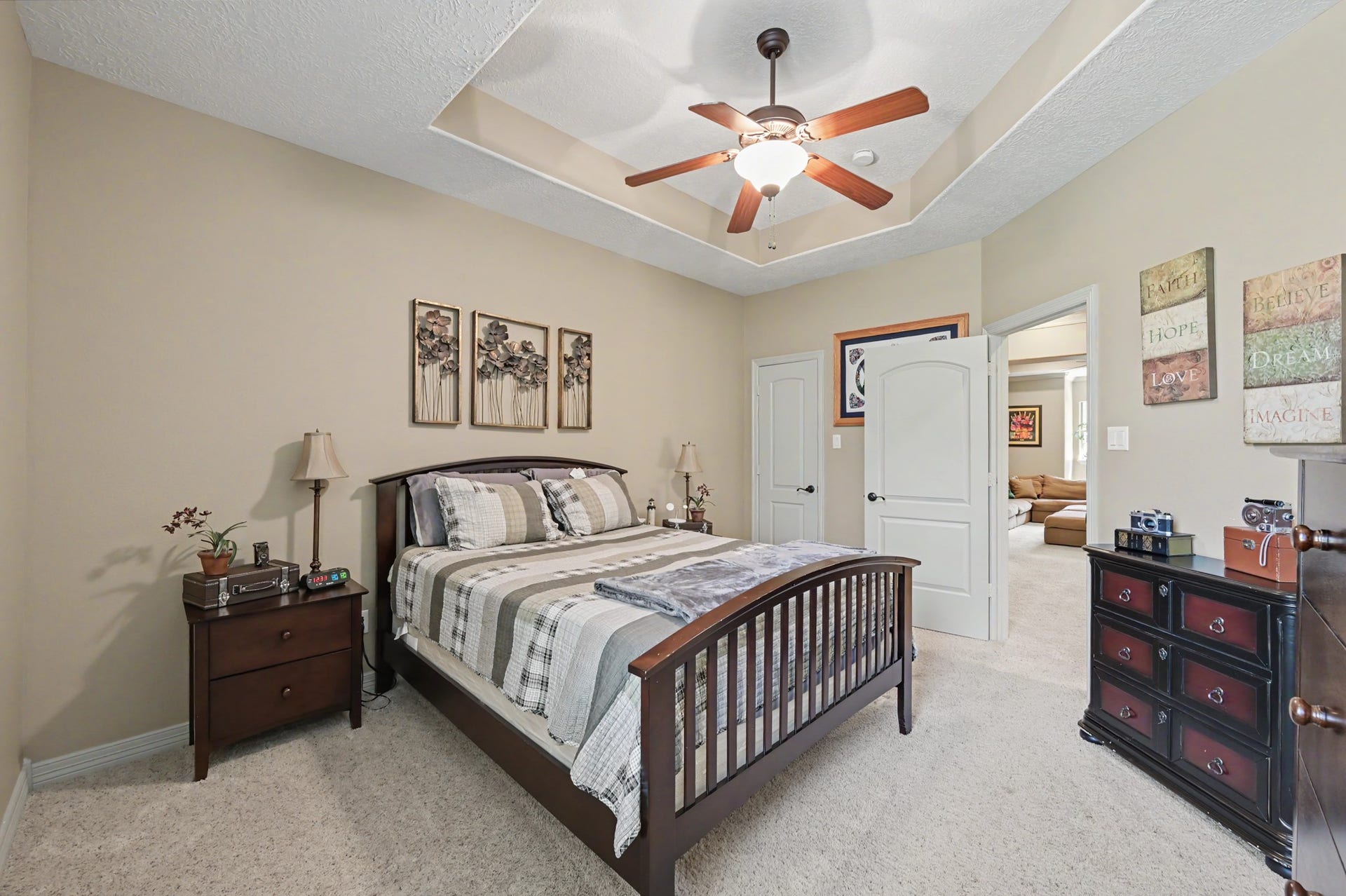 27706 Braydon Court, Spring, TX 77386 Charming bedroom featuring a tray ceiling with a stylish fan, complemented by warm neutral tones and plush carpeting for a cozy ambiance.