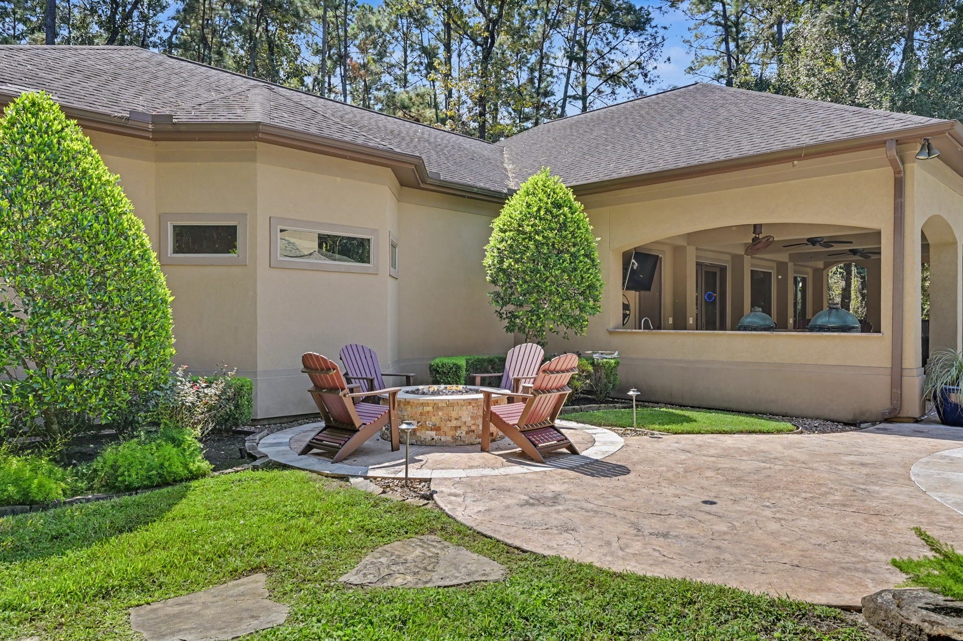 27706 Braydon Court, Spring, TX 77386 Charming backyard retreat featuring a cozy fire pit surrounded by Adirondack chairs, lush landscaping, and a covered patio perfect for outdoor entertaining.