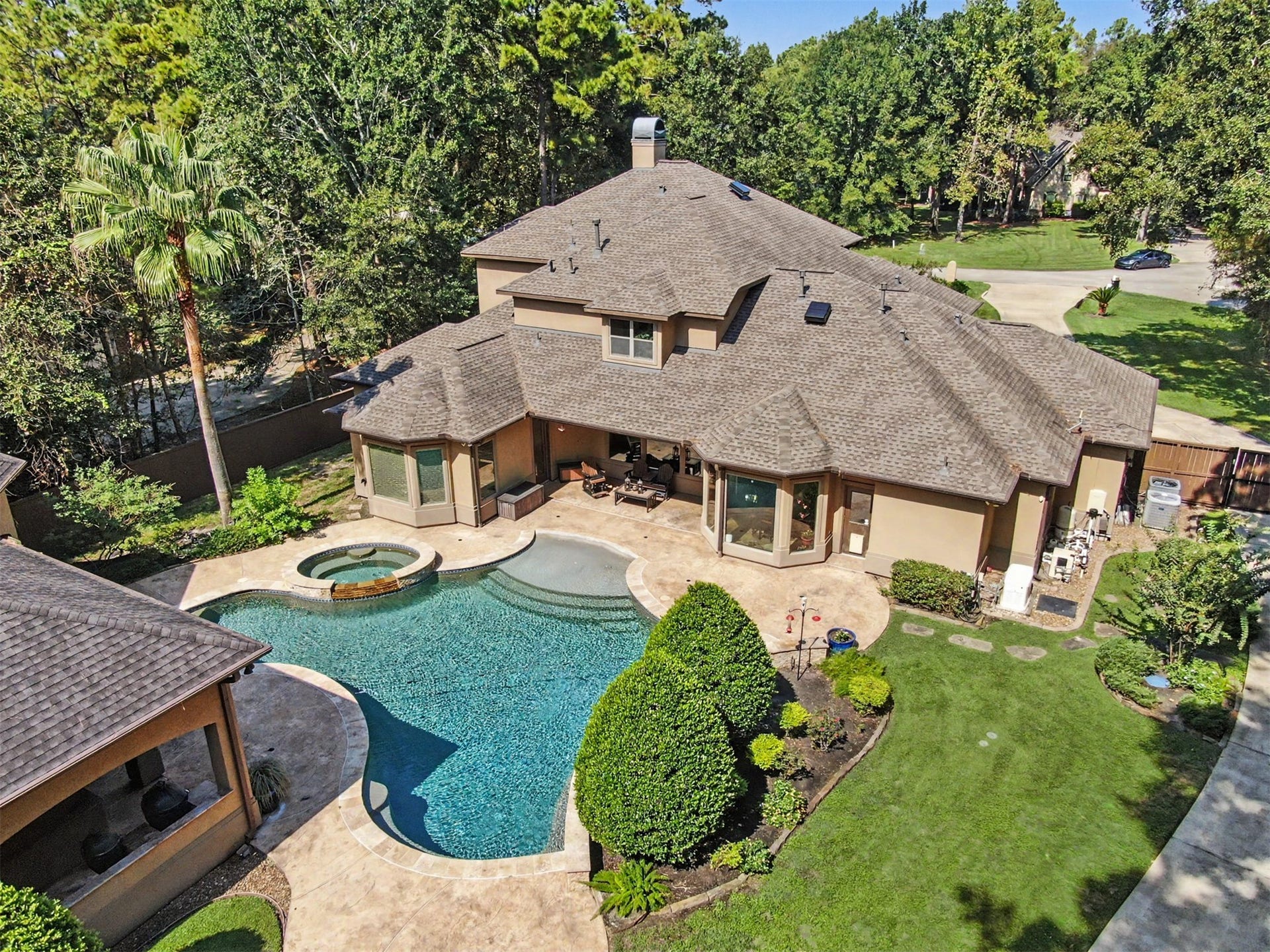 27706 Braydon Court, Spring, TX 77386 Luxurious home with a stunning backyard oasis featuring a sparkling pool, spa, and spacious patio area, surrounded by lush greenery for ultimate privacy and relaxation.
