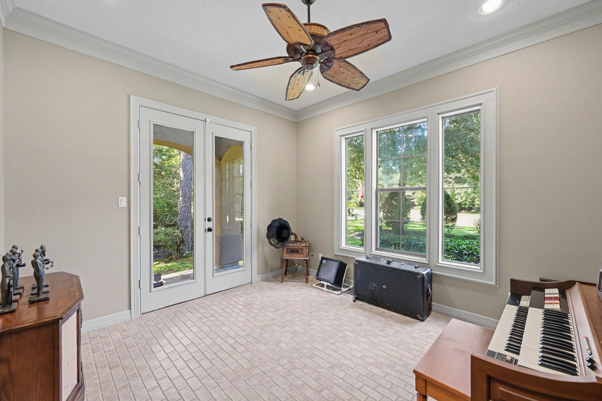 27706 Braydon Court, Spring, TX 77386 Bright and inviting sun/music room featuring large windows overlooking lush greenery, with elegant French doors and a charming ceiling fan for added character.