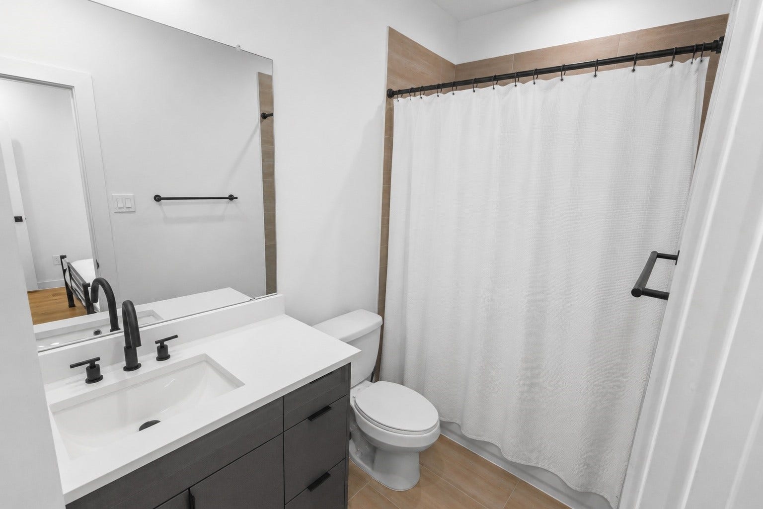 6742 Peerless Street, #B, Houston, TX 77021 Bright ensuite first floor bath showcases crisp white quartz countertops, contemporary cabinetry, matte black hardware, and a full tub and shower combination. Neutral finishes provide a clean, modern look that complements the homes cohesive design throughout.