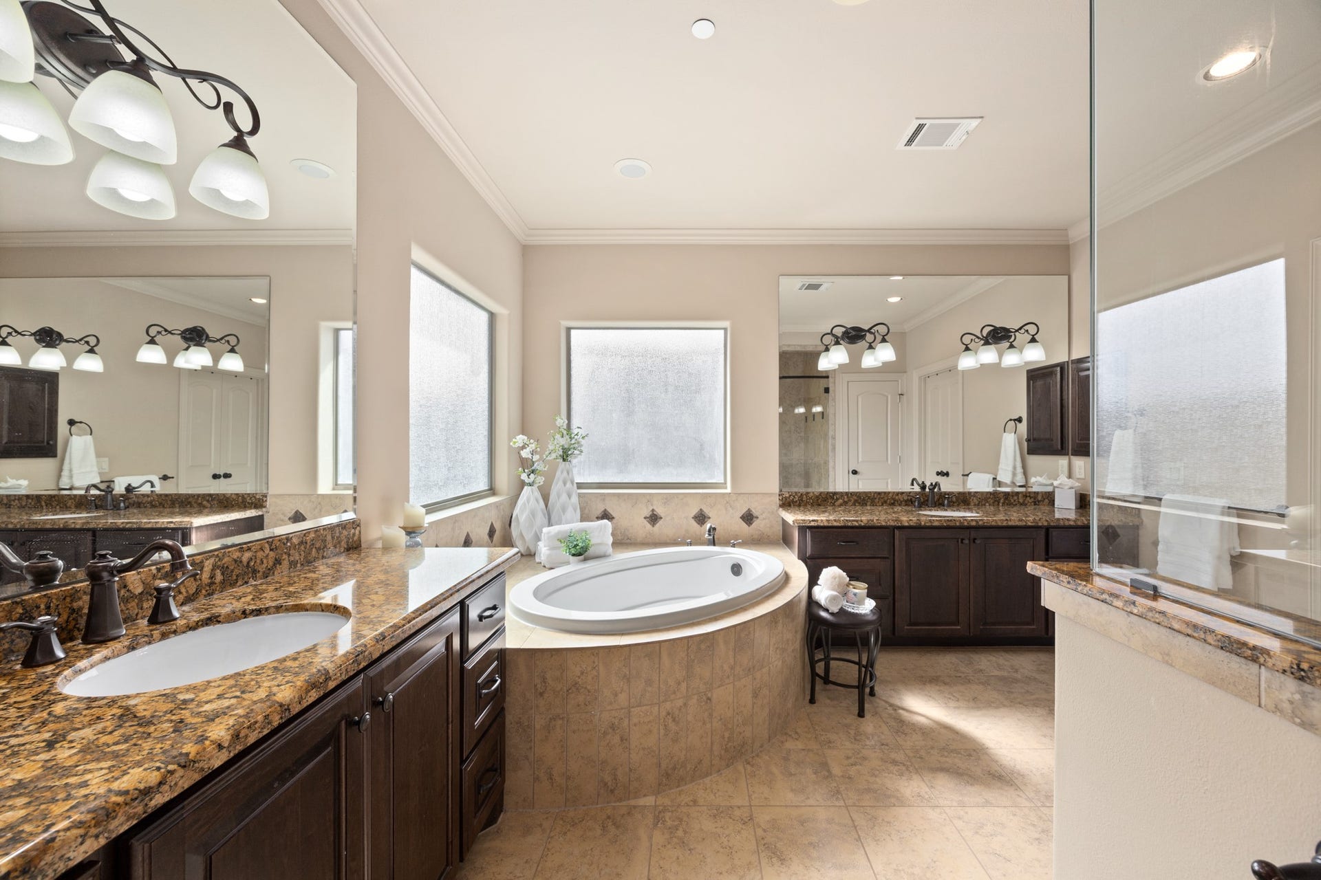 4315 Serenade Terrace Drive, Missouri City, TX 77459 This spacious primary bathroom features a luxurious soaking tub, dual sinks with granite countertops, elegant dark wood cabinetry, and ample natural light from large windows. Perfect for relaxation and functionality.