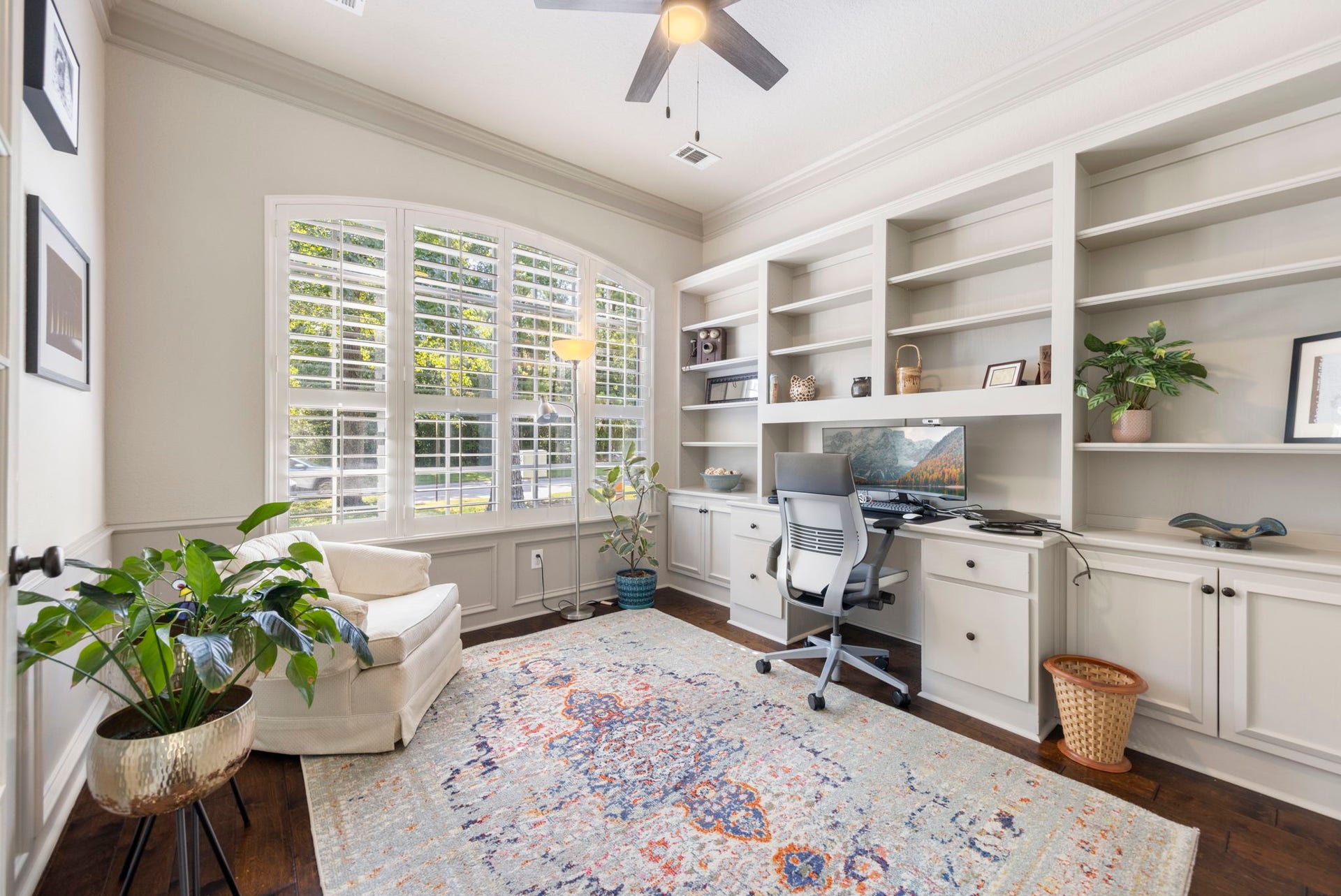 6 N Cochrans Green Circle, The Woodlands, TX 77381 Private study with an arched, shuttered window, floor-to-ceiling built-ins, a custom desk, and wainscoting.