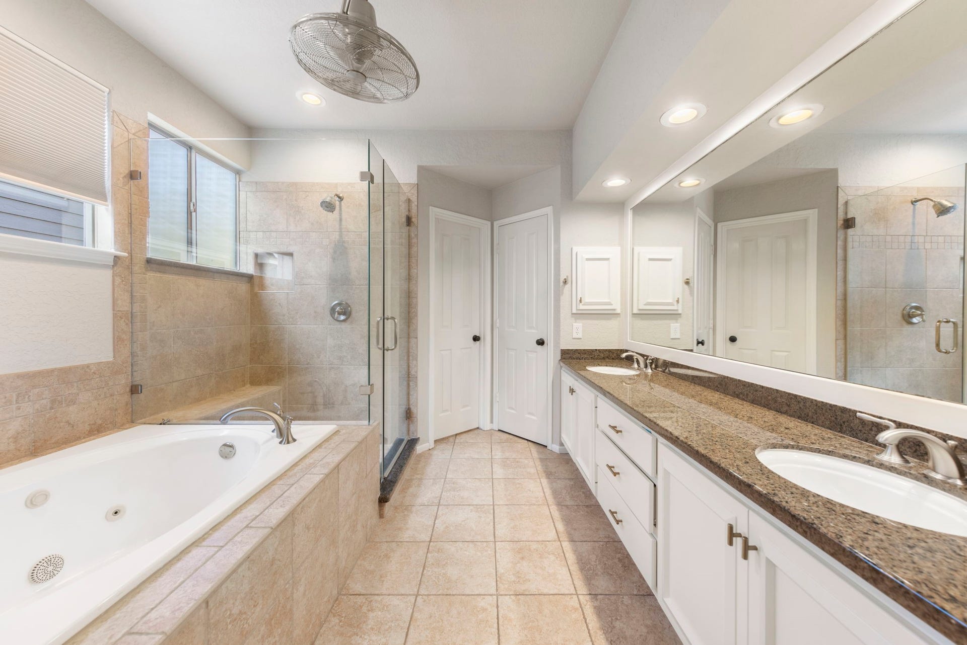 6 N Cochrans Green Circle, The Woodlands, TX 77381 Spa-like primary bath boasting a jetted soaking tub, frameless glass shower with bench, dual-sink vanity.