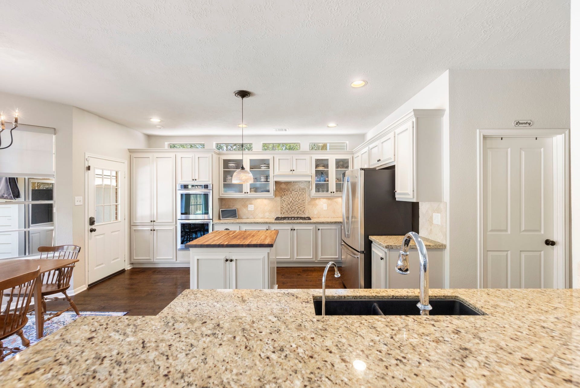 6 N Cochrans Green Circle, The Woodlands, TX 77381 Expansive granite breakfast bar with dual-basin sink opens to the kitchen, with convenient access to the utility room.