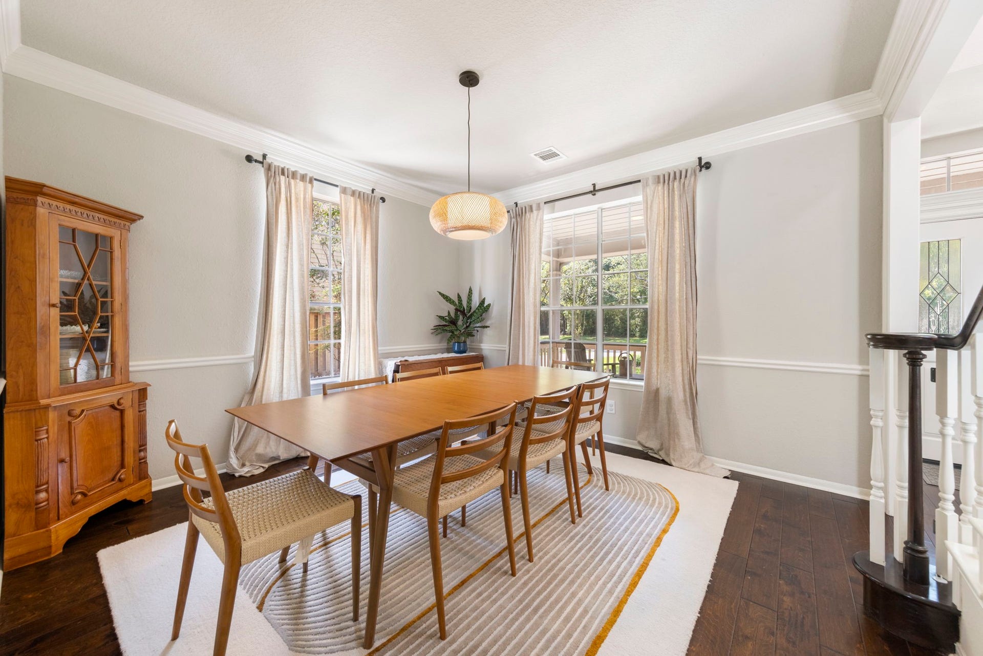 6 N Cochrans Green Circle, The Woodlands, TX 77381 Refined formal dining room with layered millwork, chair rail, and twin windows framing views of the porch and greenery.