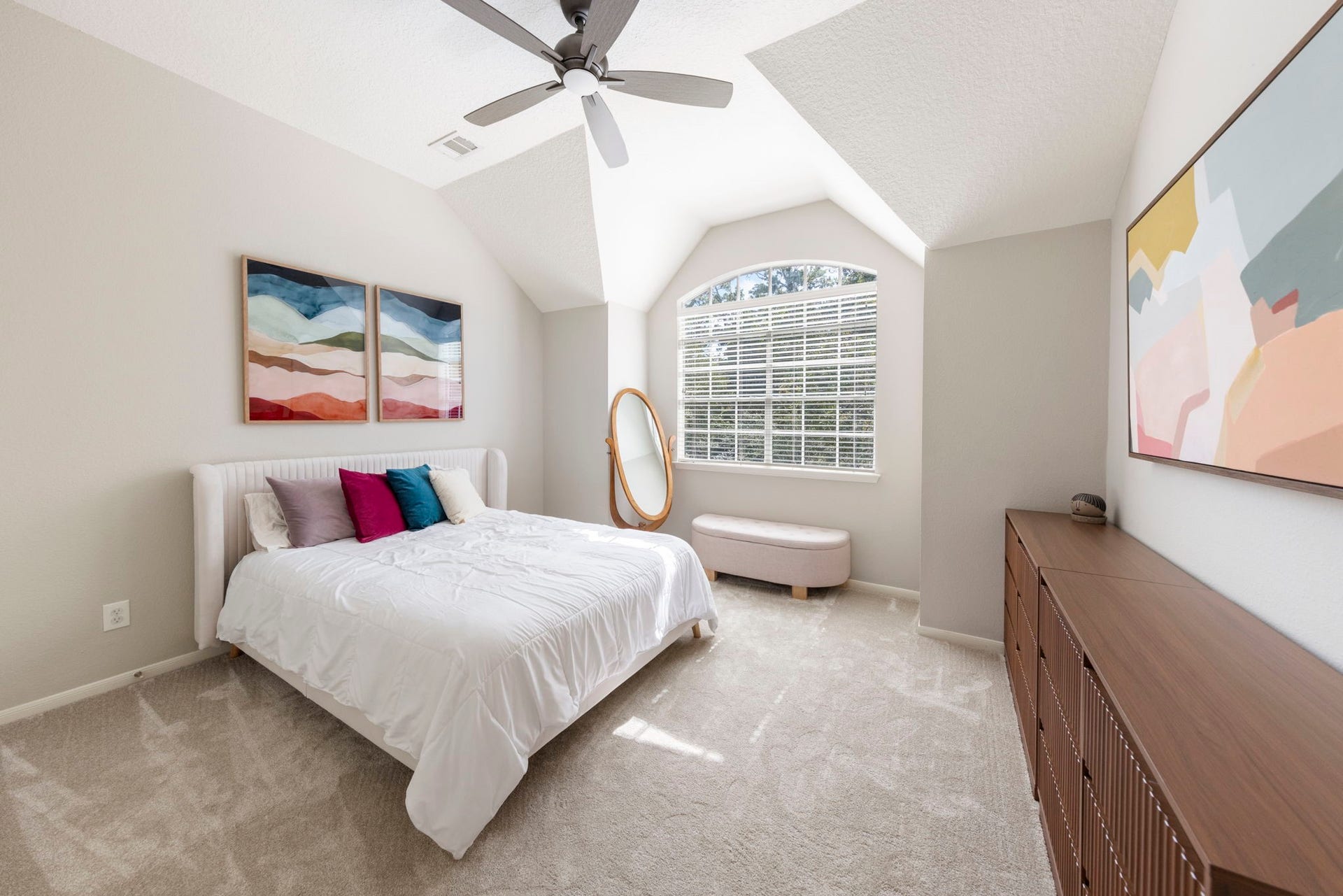 6 N Cochrans Green Circle, The Woodlands, TX 77381 Serene bedroom featuring a striking vaulted ceiling, an arched window with treetop views, and soft neutral carpet.
