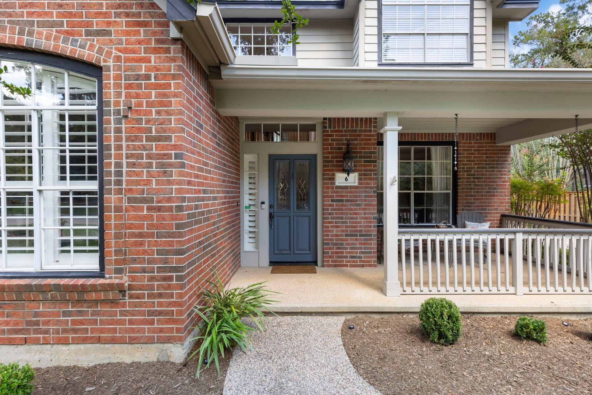 6 N Cochrans Green Circle, The Woodlands, TX 77381 Leaded-glass front door with transom and sidelight, lantern-style sconce, and an exposed-aggregate walkway that sets a gracious first impression.