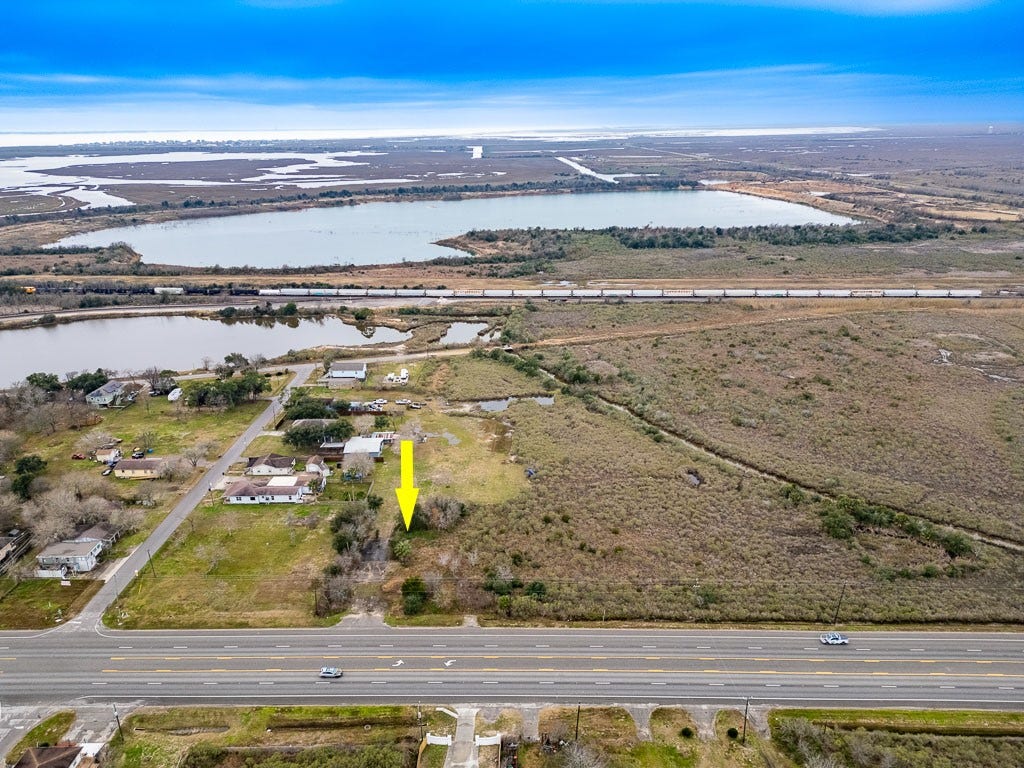 4811 Highway 6, Hitchcock, TX 77563 Wide aerial view with arrow identifying the subject property directly along Highway 6 with surrounding wetlands, waterways, and rail corridor visible.