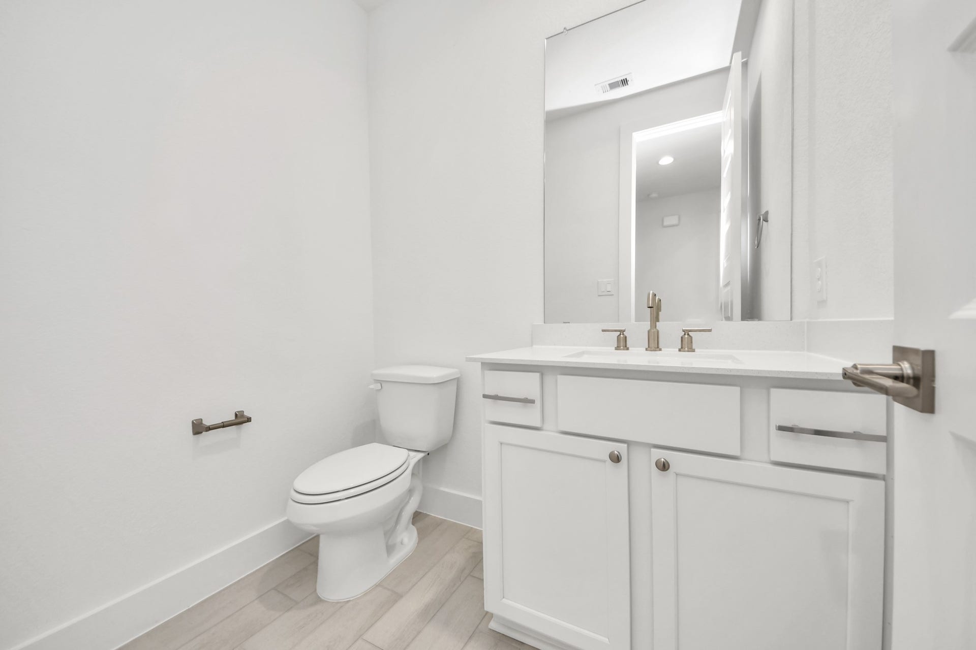 24747 Skerne Woods Drive, Spring, TX 77373 Sophisticated half bathroom adorned with contemporary finishes. The elegant 5-panel door welcomes you to a space where style meets functionality. Notice the sleek hardware accents that add a touch of modern charm. The vanity boasts light-colored countertops, beautifully complemented by a tasteful vanity light, creating a well-lit and inviting atmosphere. Sample photo of completed home with similar floor plan. Actual colors and selections may vary.