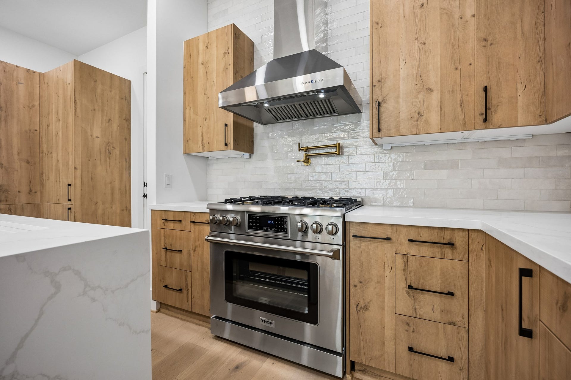 4305 Floyd Street, #B, Houston, TX 77007 Kitchen offers a stainless steel gas range, chimney-style vent hood, pot filler and full-height tile backsplash.