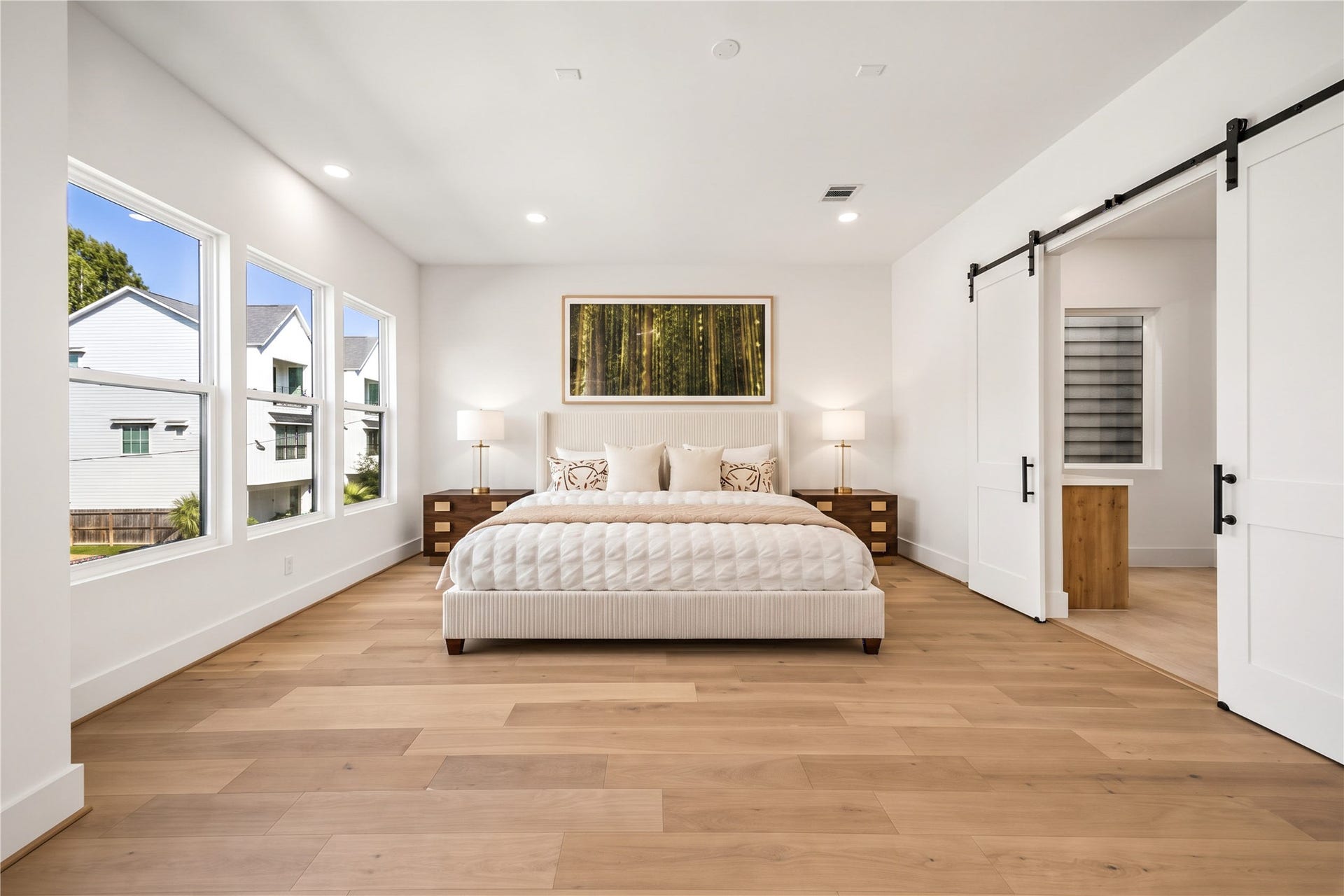 4305 Floyd Street, #B, Houston, TX 77007 Primary suite spacious retreat featuring wood flooring, recessed lighting and a sliding barn door. (virtual staging)