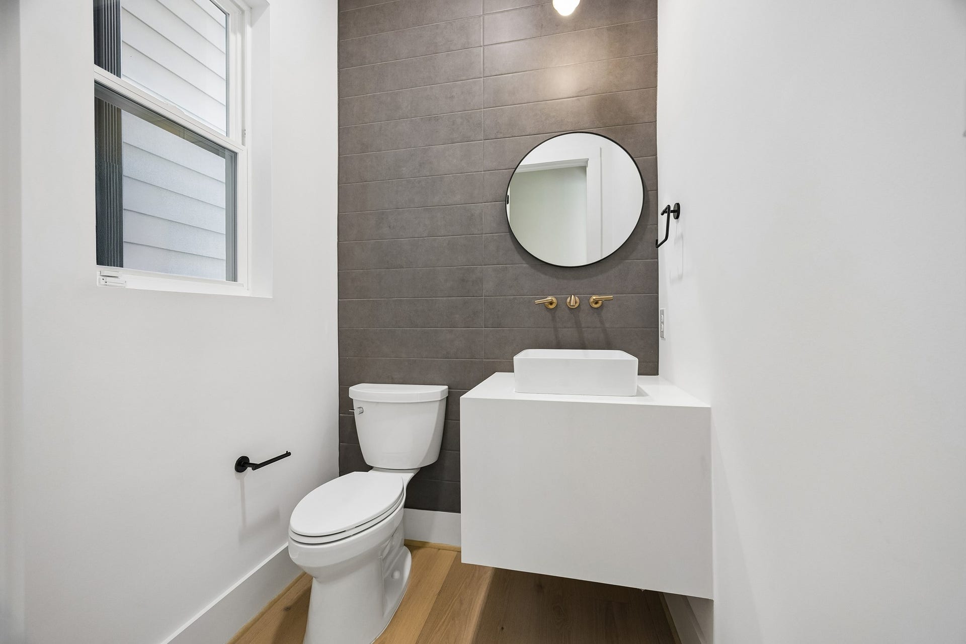 4305 Floyd Street, #B, Houston, TX 77007 Powder room features a floating vanity, round mirror, and tile accent wall.