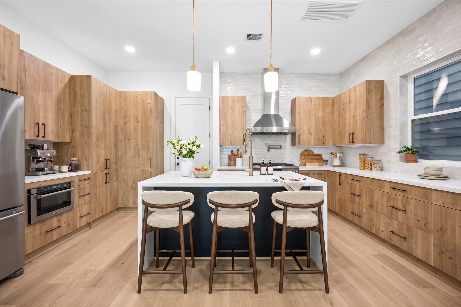 4305 Floyd Street, #B, Houston, TX 77007 Kitchen features a double edge waterfall island, custom wood-tone cabinetry, designer pendant lighting and quartz counters. (virtual staging)