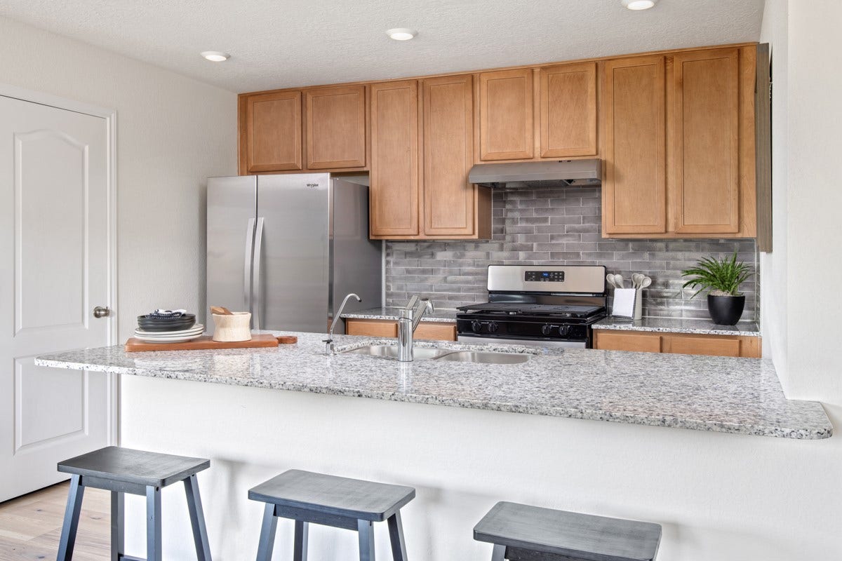 A true chefs dream, this kitchen boasts high ceilings, Woodmont Cody cabinets in Toffee stain, granite countertops in Luna Pearl, stainless steel appliances, a modern tile backsplash, recessed lighting, an extended countertop for a breakfast bar, and a pantryall with a clear view of the spacious Great Room.