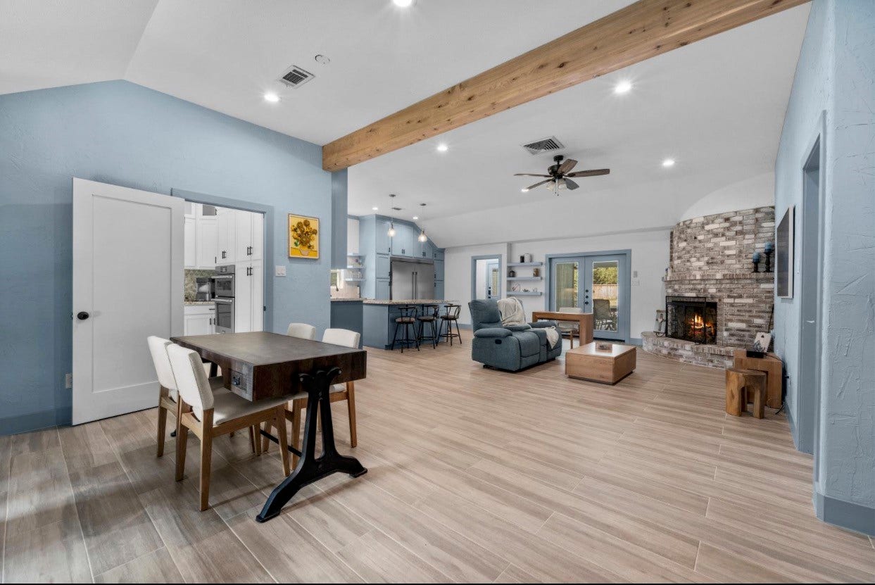 12710 Mutiny Lane, Tomball, TX 77377 Open living and dining spaces feature a vaulted ceiling, exposed beam, and views toward the fireplace and kitchen.