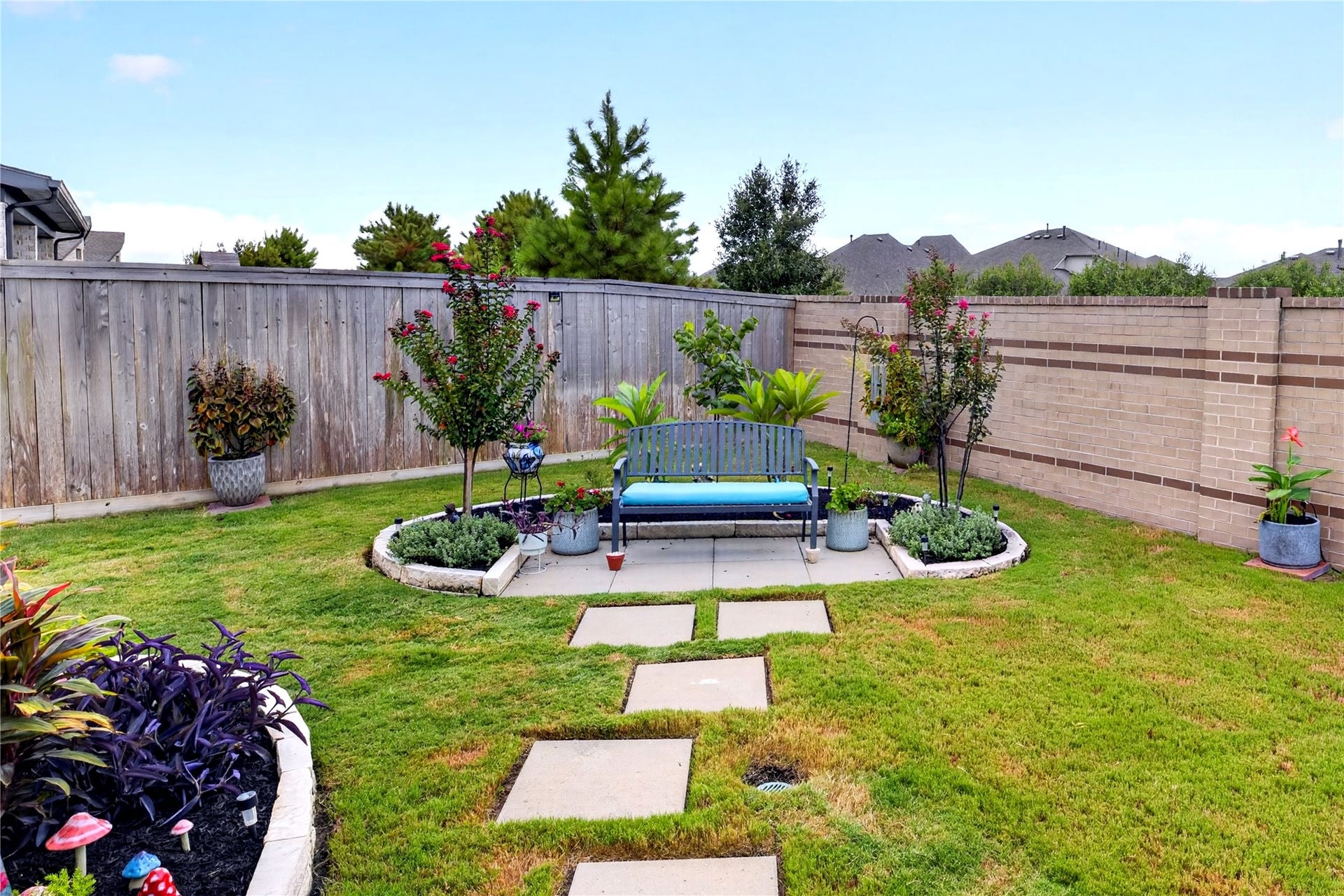 11351 Cosmopolitan Drive, Cypress, TX 77433 Beautiful landscaped backyard, mature greenery, colorful garden beds and a charming seating area. A stepping stone pathway leads to the private garden retreat, creating a peaceful space for relaxing or entertaining outdoors.