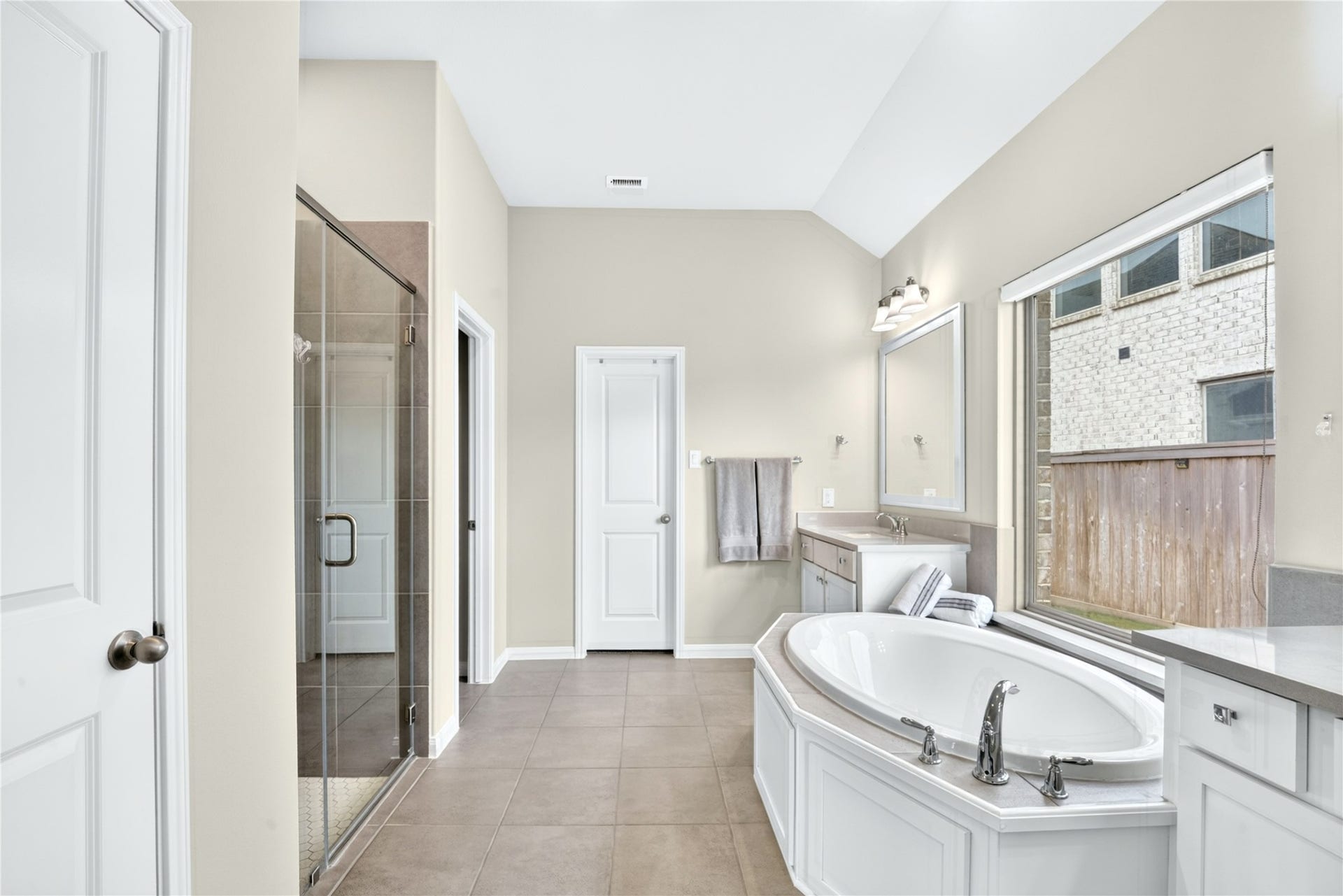 11351 Cosmopolitan Drive, Cypress, TX 77433 Clean and serene, the primary bathroom offers a spa-like retreat with dual sinks, designer mirrors, a walk-in shower, and elegant tile flooring.