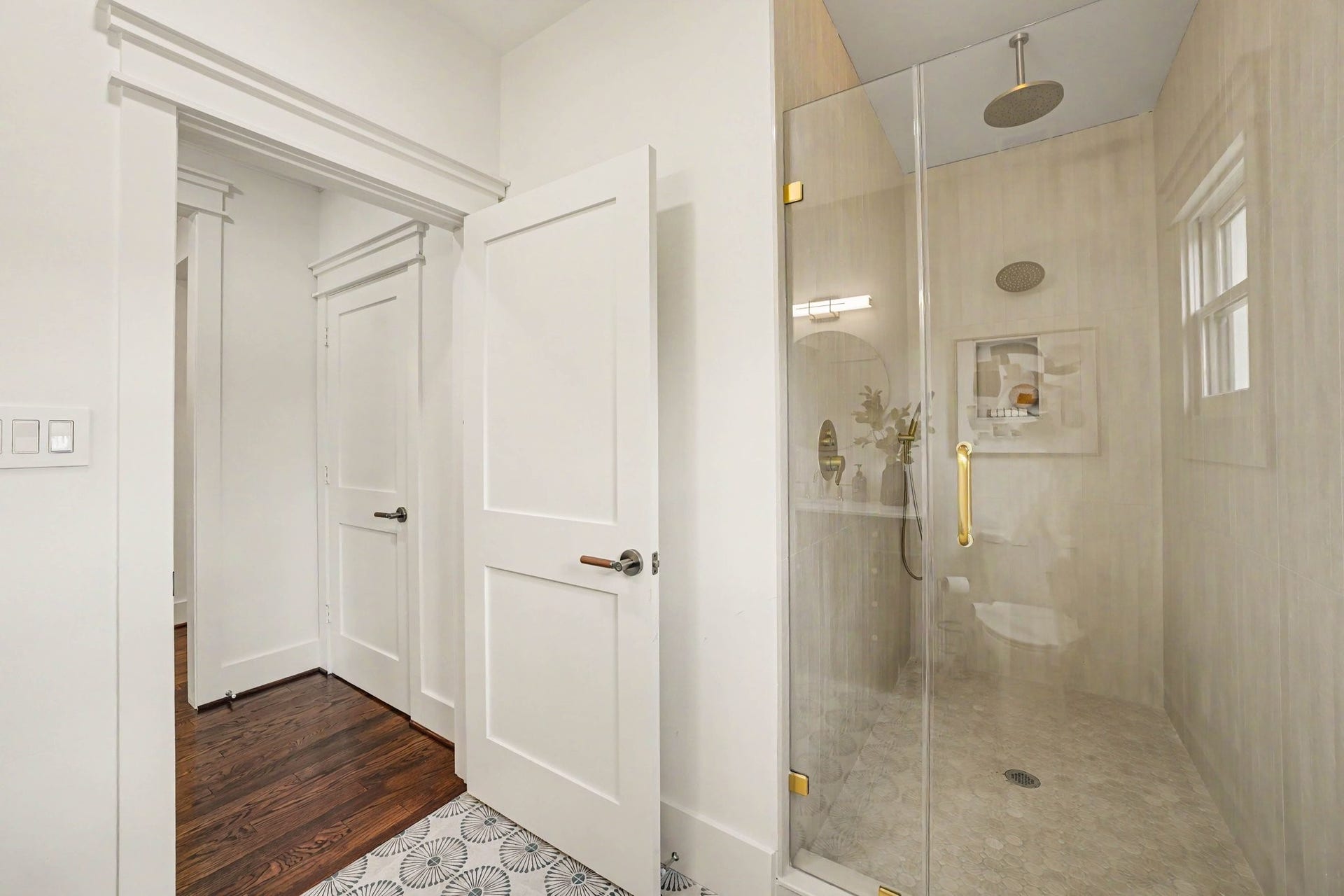 Walk-in shower with two shower heads and hand sprayer.