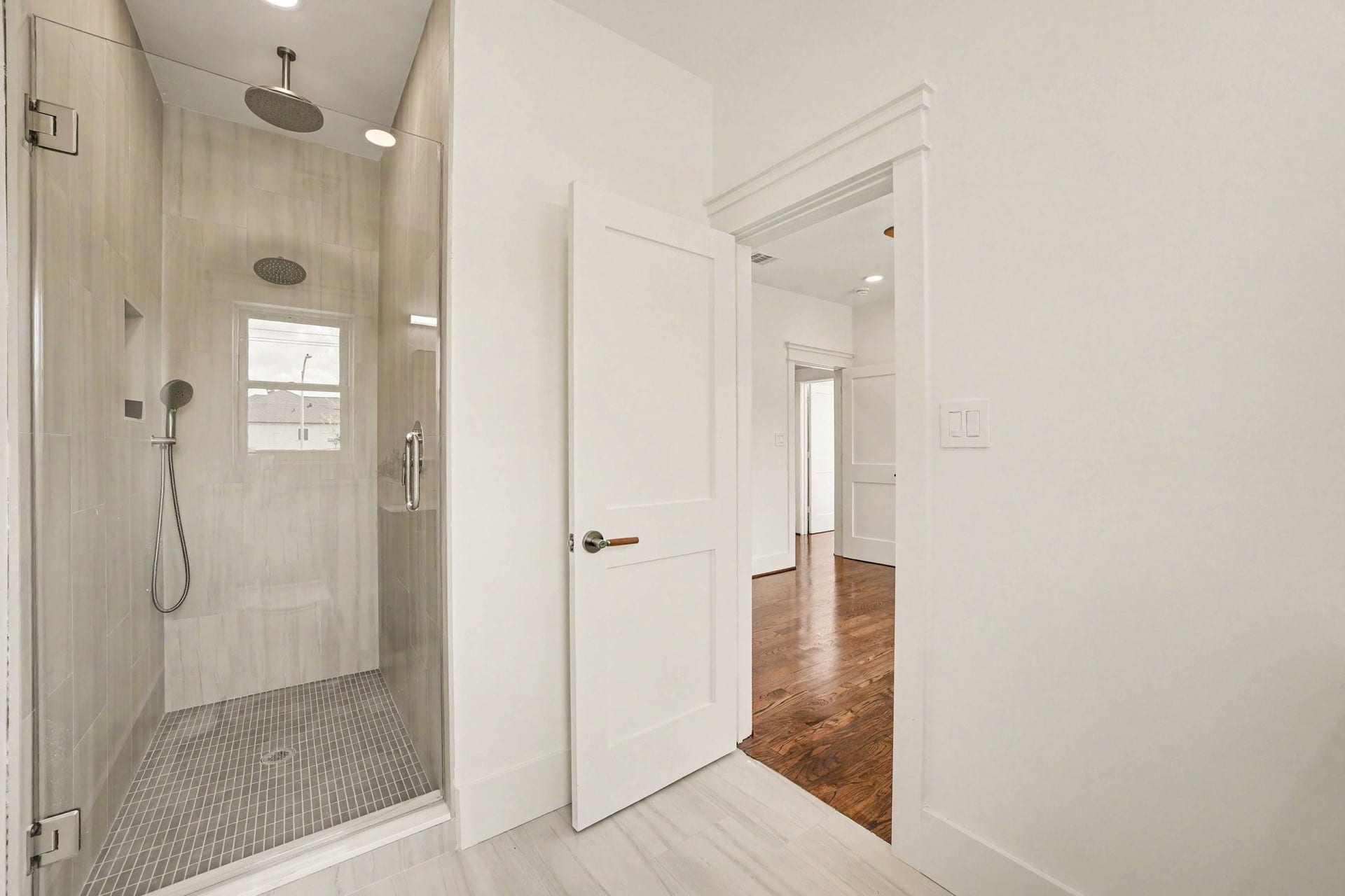 Walk-in shower with two shower heads and hand sprayer.
