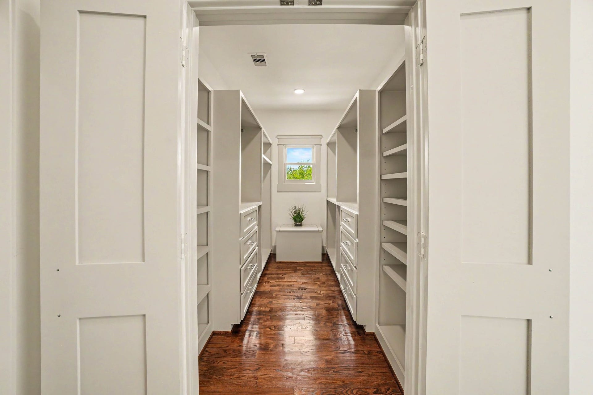Walk-in closet with adjustable shelves and storage bench.