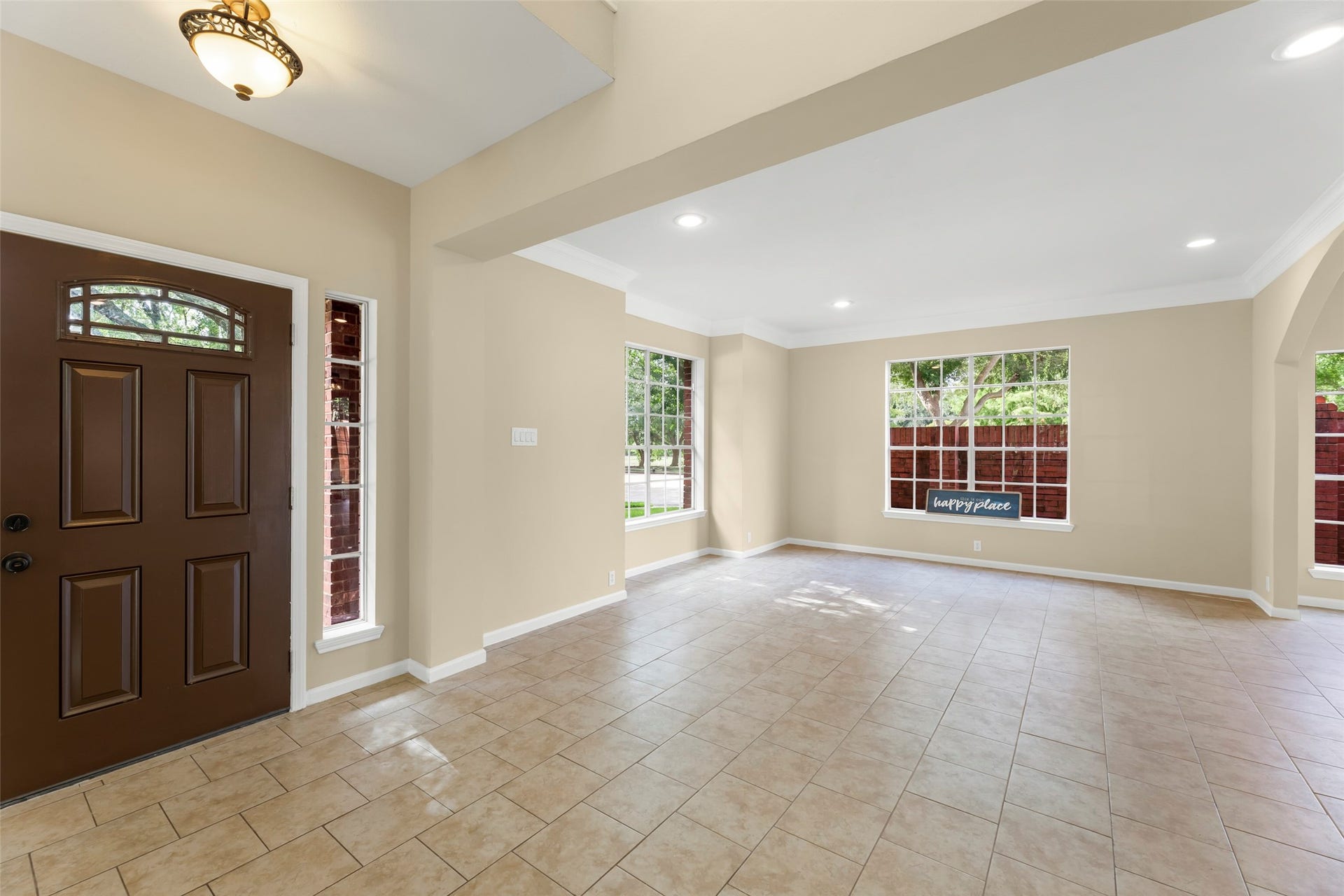 Bright and airy family room features large windows, tiled floors, and a welcoming entryway with a classic wooden door. The open layout and neutral tones create a warm and inviting atmosphere.