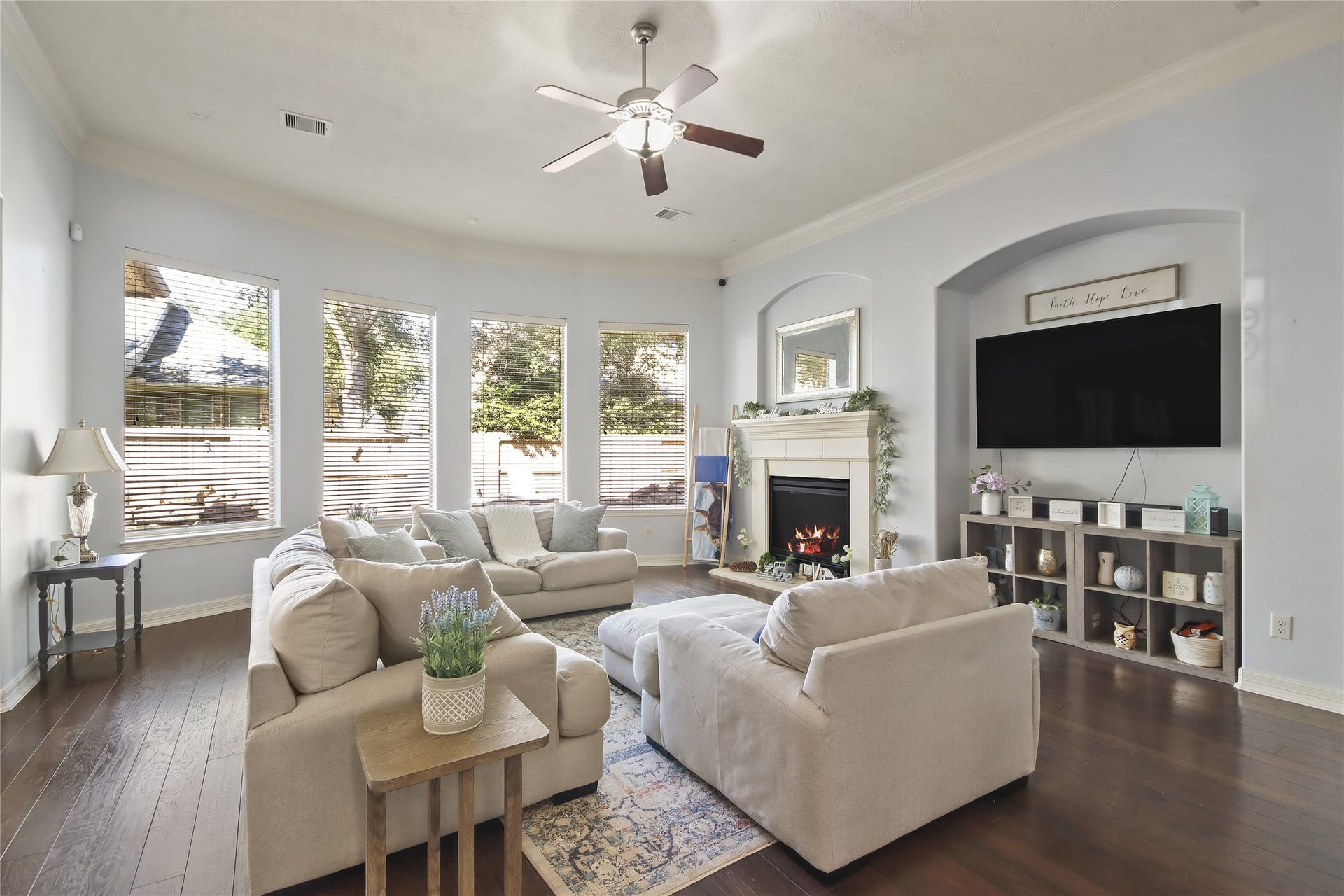 Spacious family room features elegant hardwood floors and a cozy fireplace with abundant natural light from the large windows.